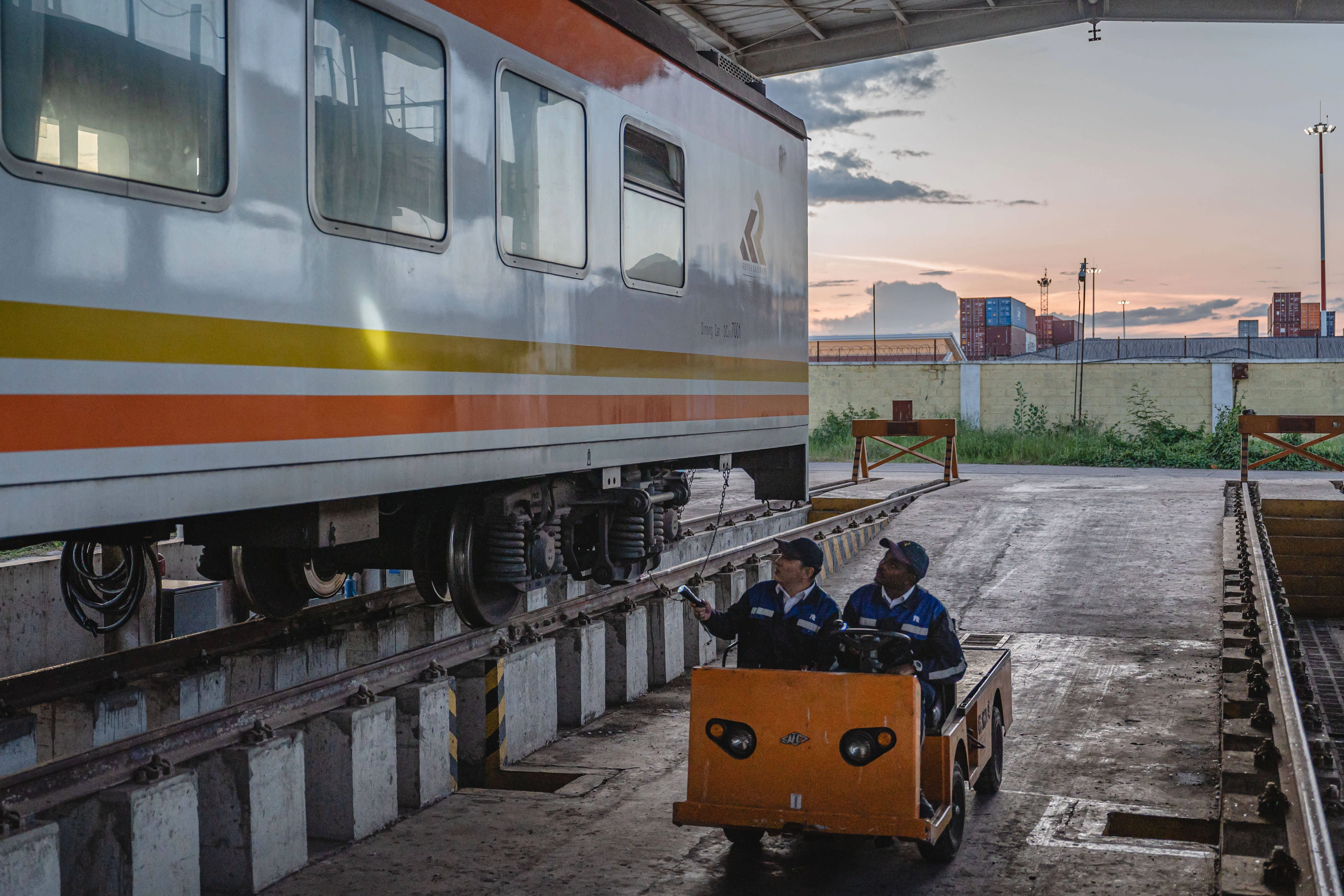 Ein chinesischer Ausbilder und ein einheimischer Auszubildender inspizieren einen Zug der Mombasa-Nairobi Railway in Nairobi, Kenia.