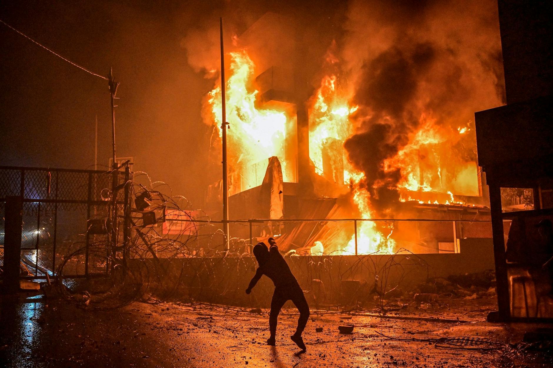 Ein Demonstrant wirft nach dem Angriff auf das Krankenhaus im Gazastreifen Steine auf ein brennendes Gebäude in der Nähe der US-Botschaft in Beirut. 