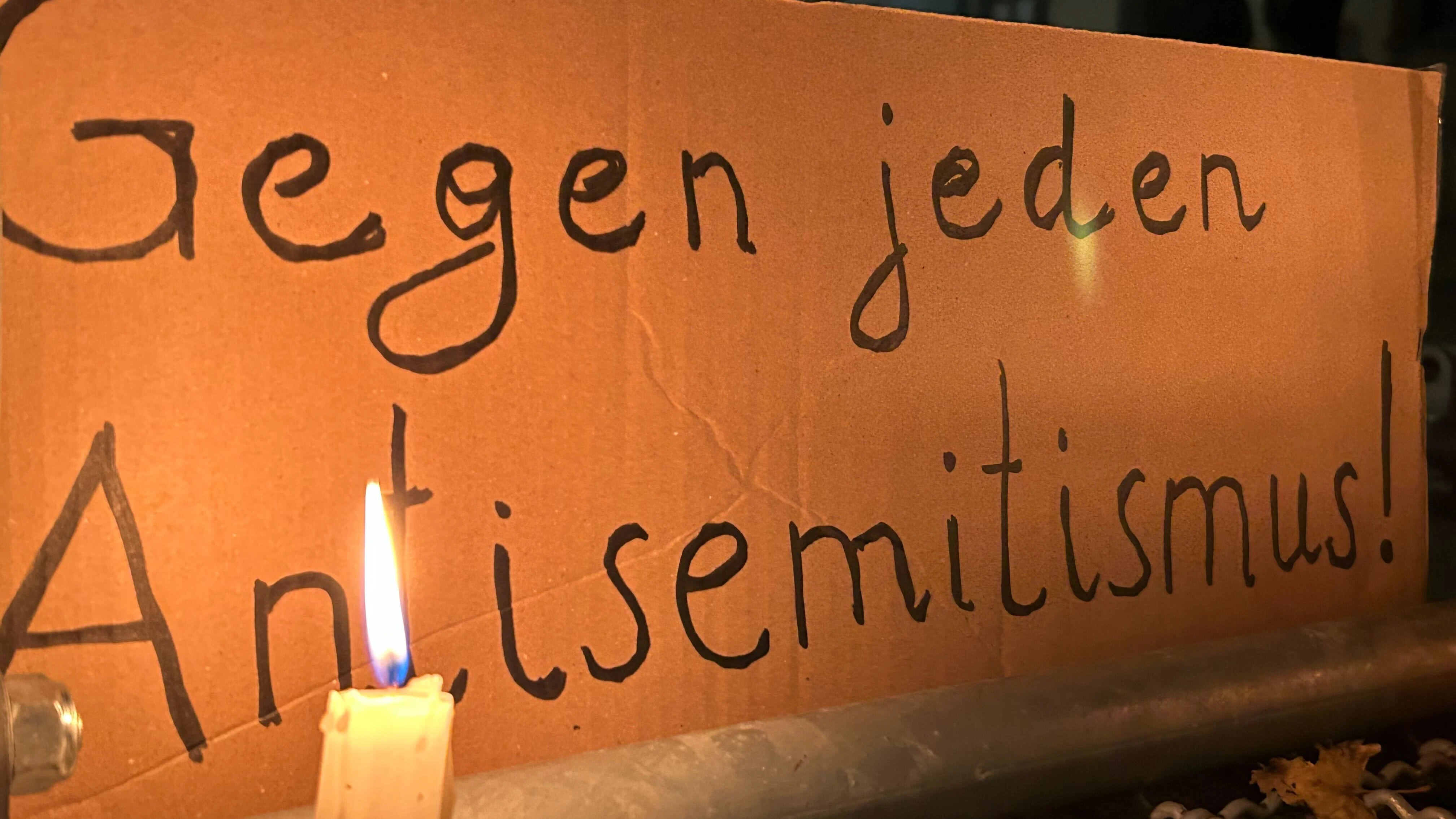 Eine brennende Kerze steht vor einem Schild mit der Aufschrift „Gegen jeden Antisemitismus“ bei einer Mahnwache gegen Antisemitismus nach dem versuchten Brandanschlag auf die Synagoge in der Berliner Brunnenstraße.&nbsp;