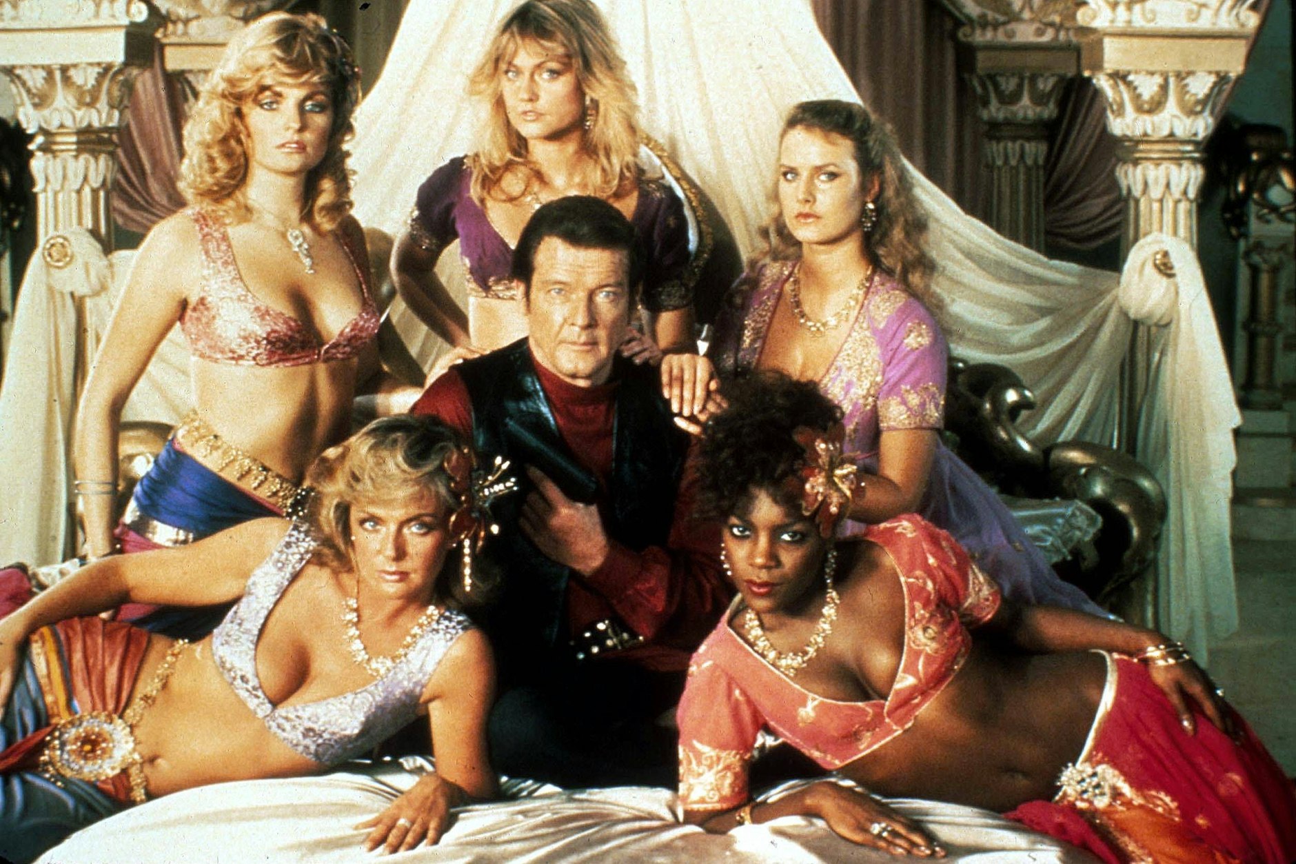 So sah man aus, so wollte man sein: Roger Moore alias James Bond 007 inmitten einer der Damen, die in„ Octopussy“ an seiner Seite spielen.