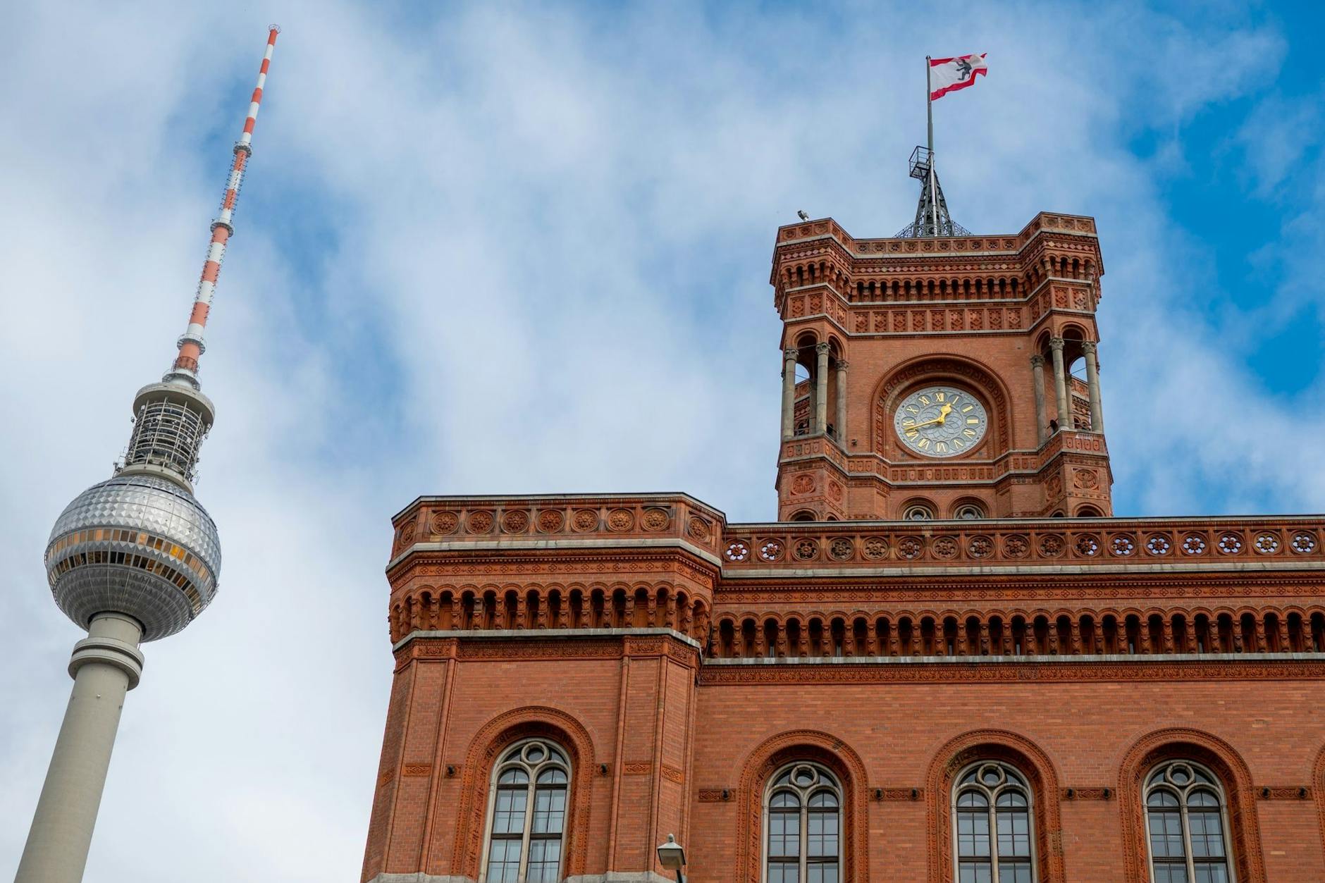 Blick auf den Fernsehturm und das Rote Rathaus mit einer Fahne mit Berliner Wappen. 