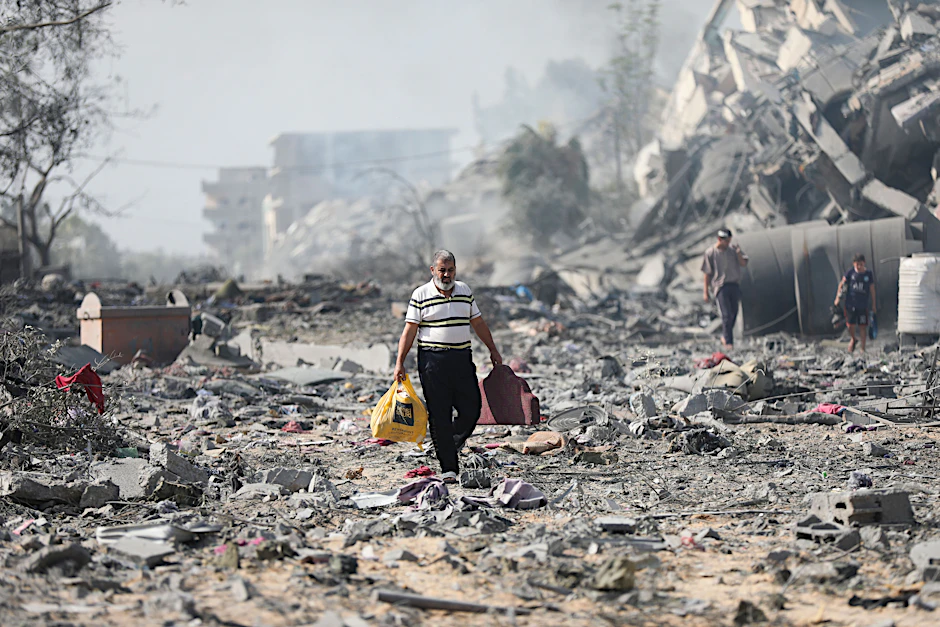 Palästinenser im Gazastreifen gehen nach einem Luftangriff an zerstörten Gebäuden vorbei.