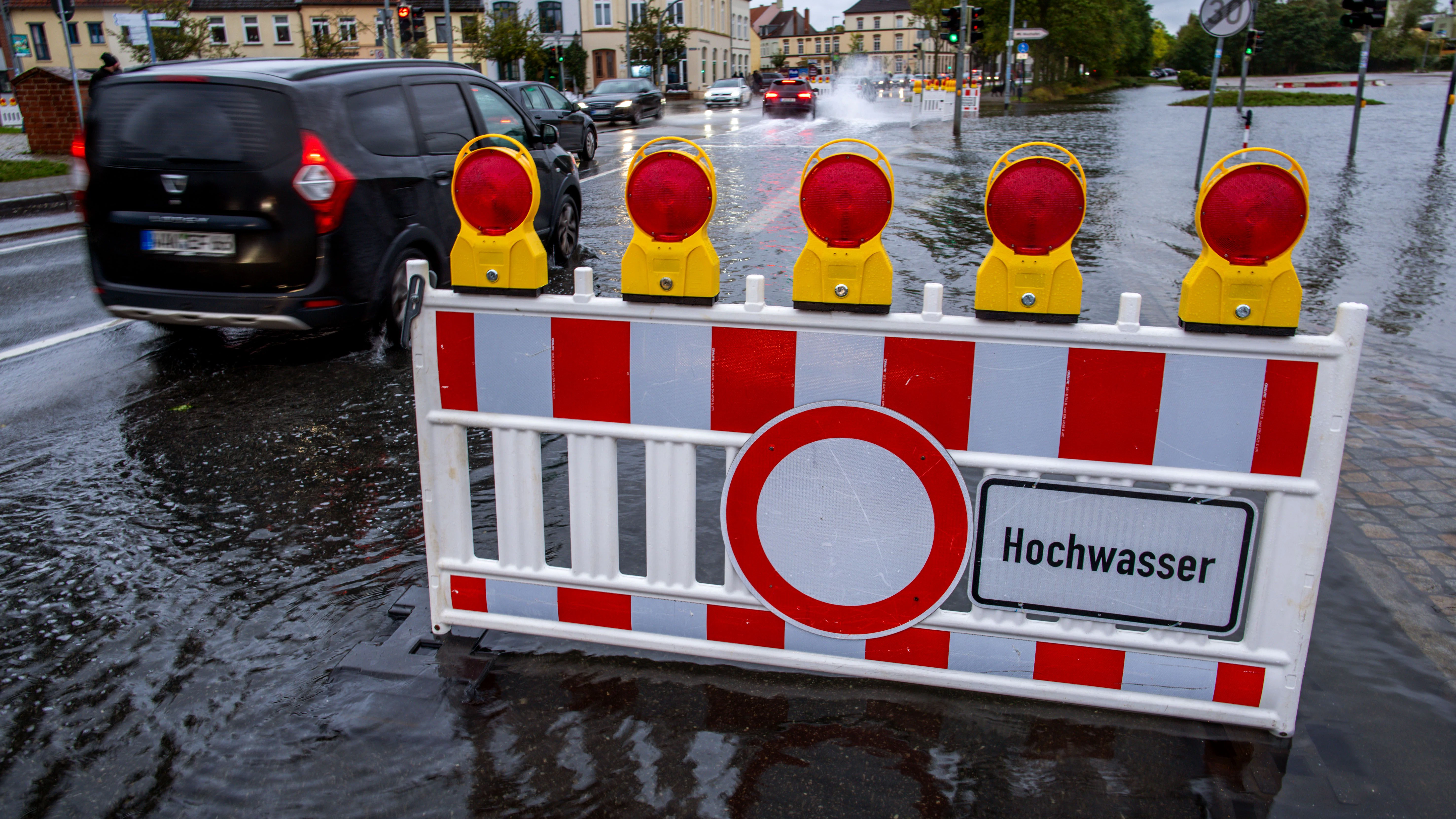 Ein Sperrschild steht im ansteigenden Hochwasser im Stadthafen. Wegen einer Sturmflut an der Ostseeküste sind Uferbereiche in der Nähe des Hafens bereits teilweise überflutet. 