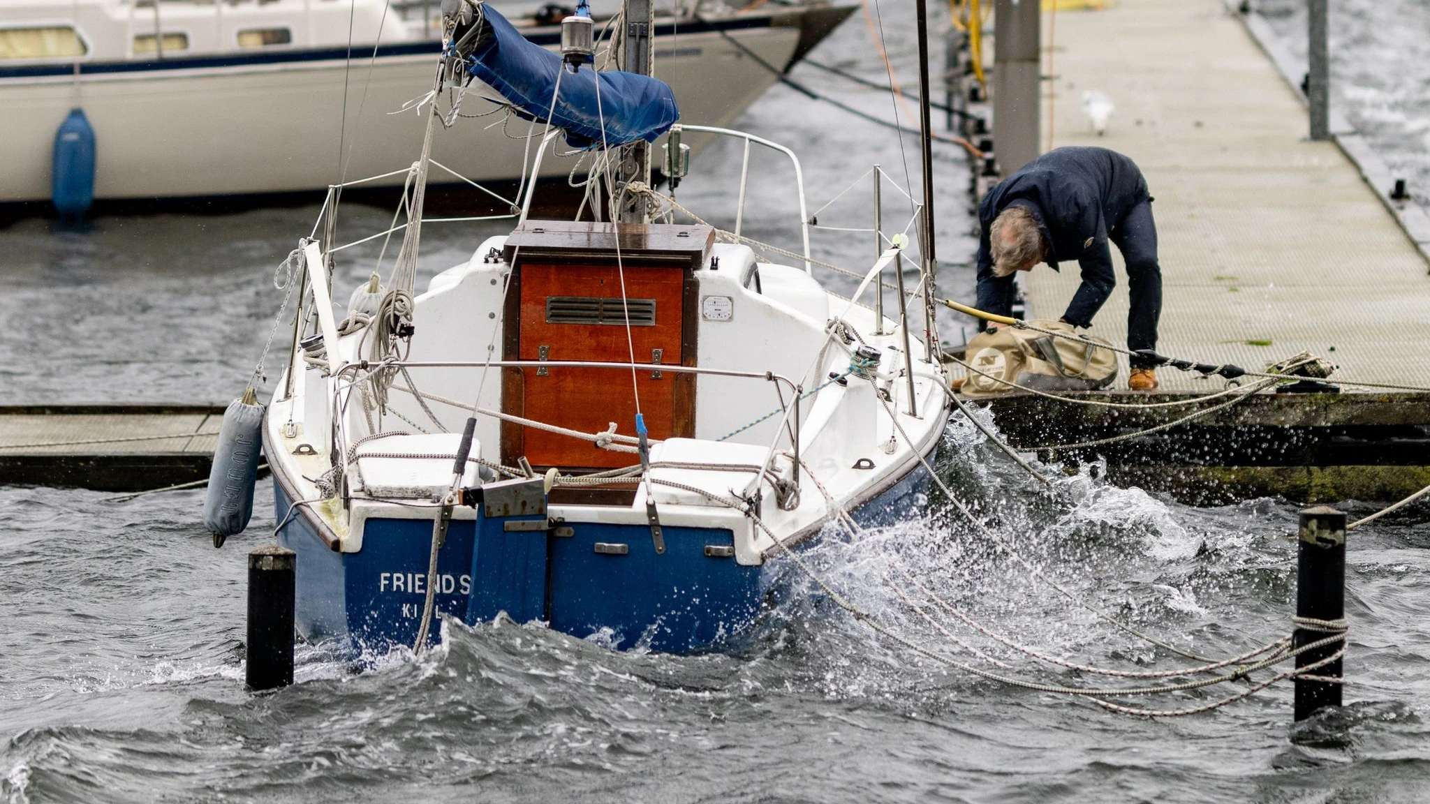 Ein Mann sichert ein Segelboot an einem Anlegesteg in der Kieler Förde.&nbsp;
