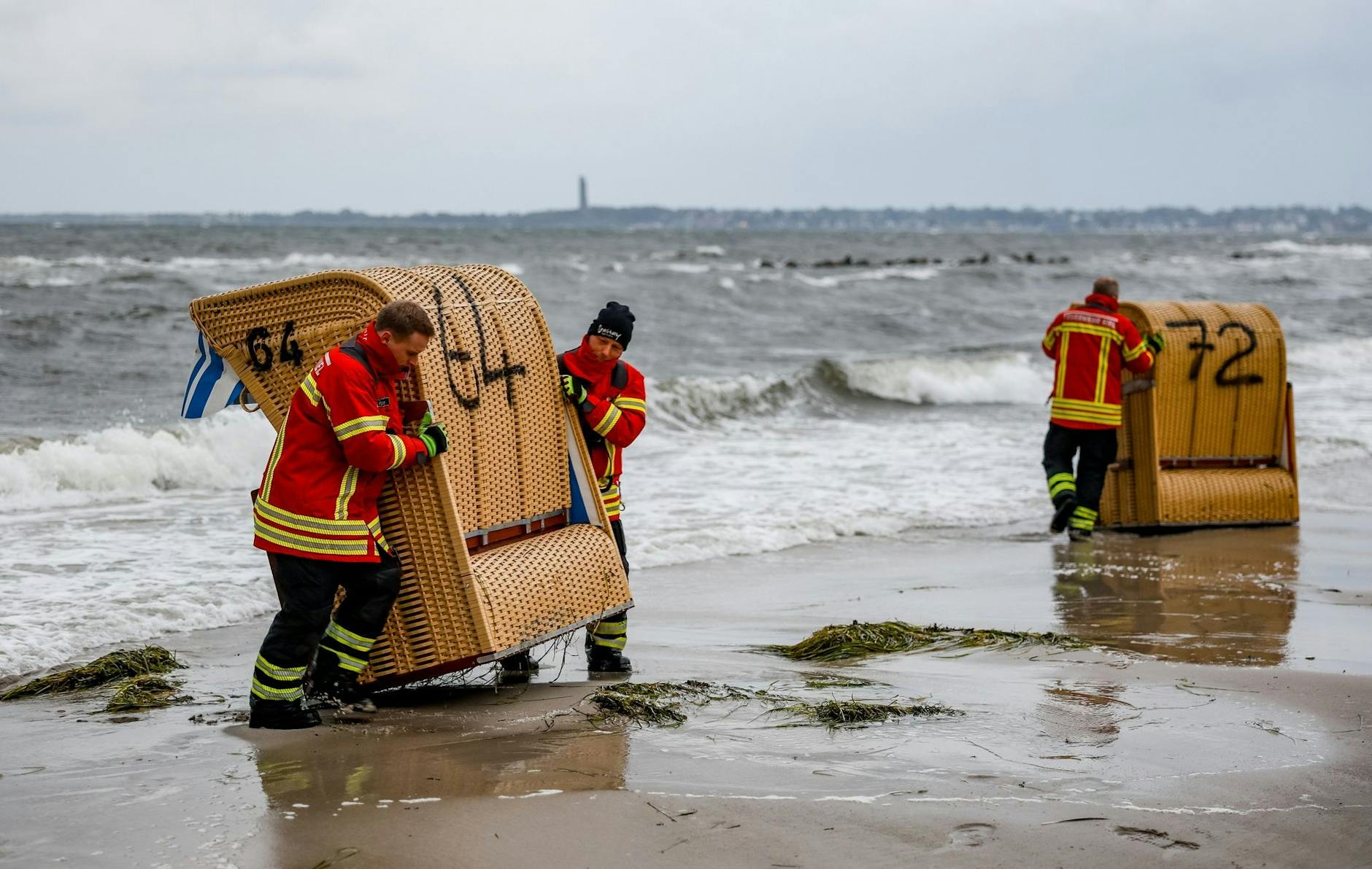 dpatopbilder - Einsatzkräfte der Feuerwehr sichern in in Kiel-Schiksee Strandkörbe vor den Flutwellen der Ostsee.