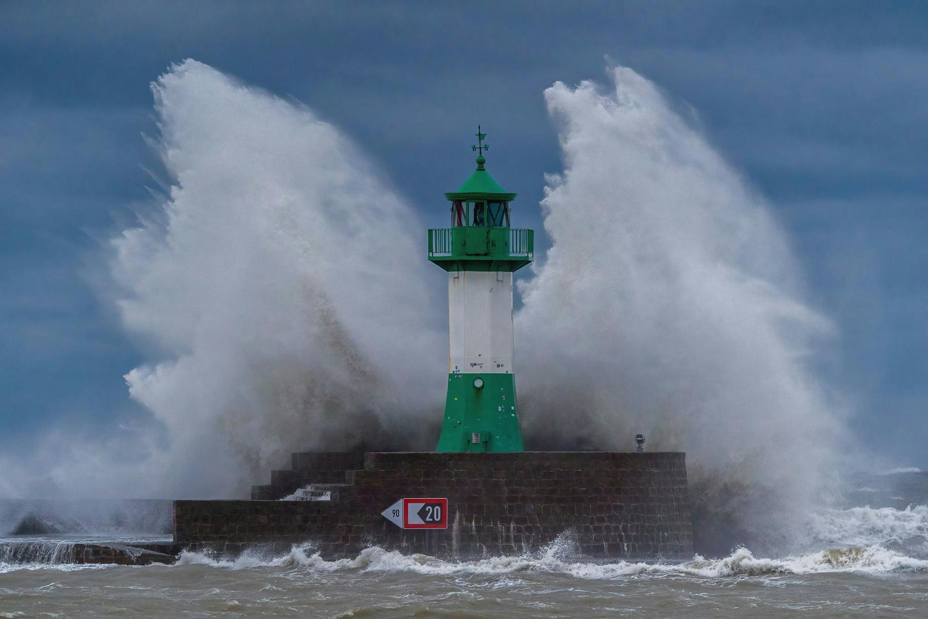 dpatopbilder - Wellen der Ostsee peitschen bei einem schweren Sturmtief an den Leuchtturm auf der Ostmole. Wegen des Sturmtiefs sind an der Ostseeküste Straßen und Uferbereiche vom Hochwasser überschwemmt worden.