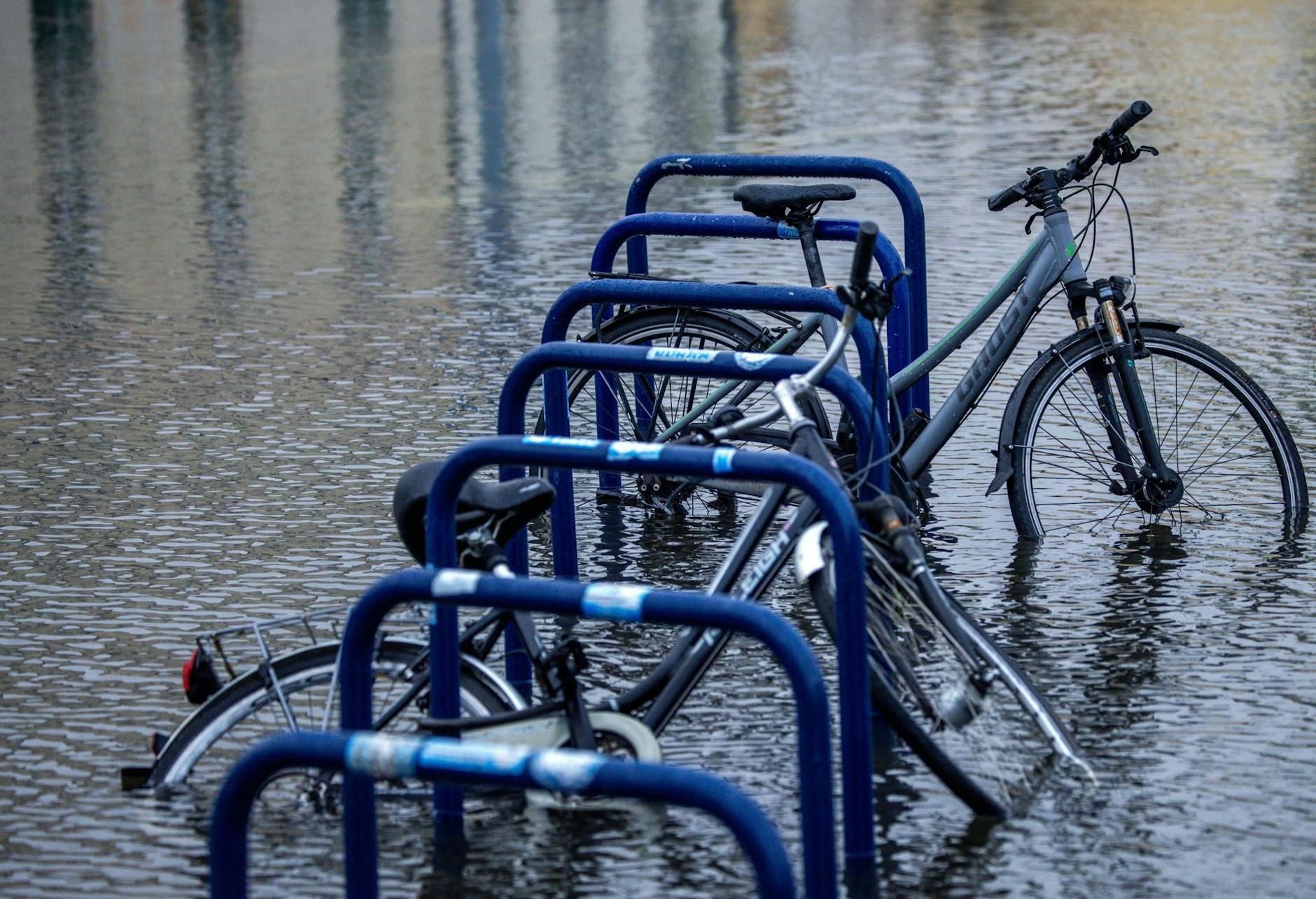 Fahrräder stehen an einer überfluteten Straßenkreuzung in der Nähe des Fischereihafens in Wismar im Wasser.