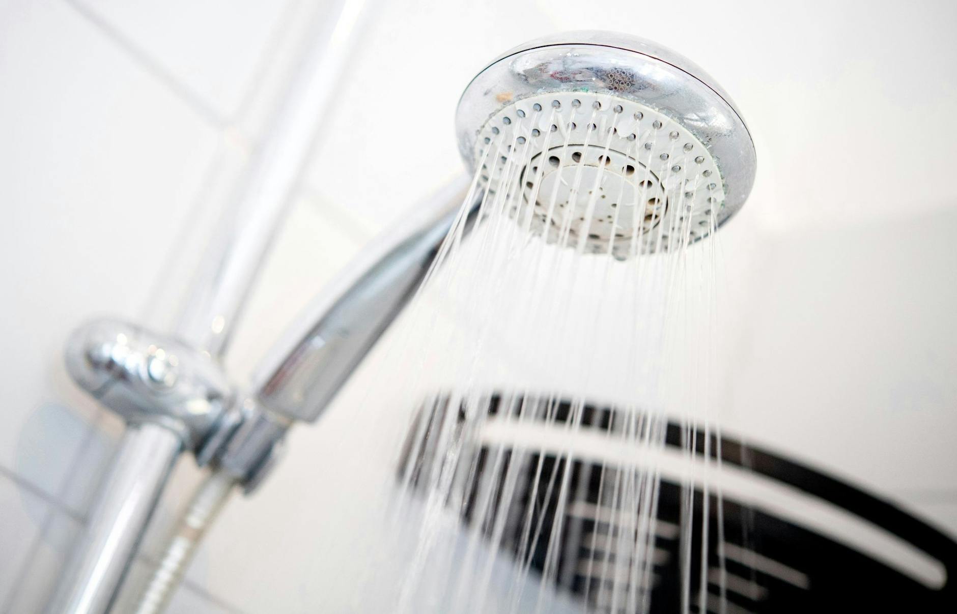 ARCHIV - Ein Duschkopf hängt in einer Dusche in einem Badezimmer.