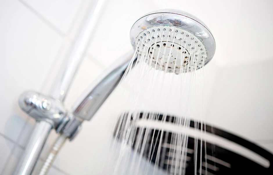 ARCHIV - Ein Duschkopf hängt in einer Dusche in einem Badezimmer.  