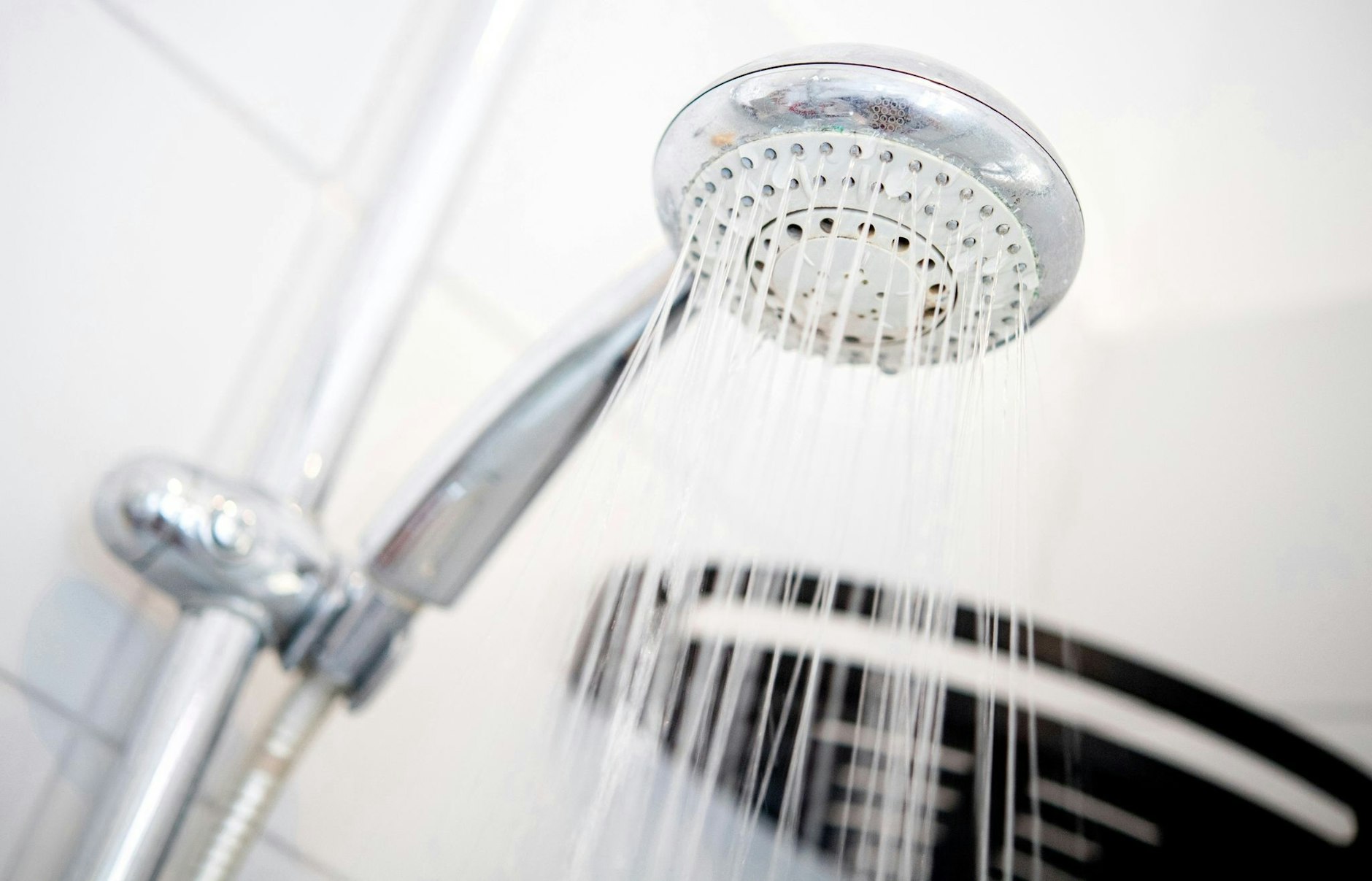 ARCHIV - Ein Duschkopf hängt in einer Dusche in einem Badezimmer.  