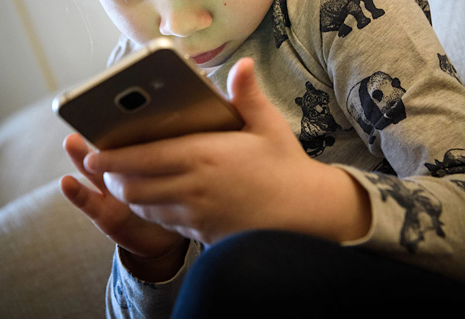 ARCHIV - Ein kleines Mädchen schaut auf das Display eines Smartphones. Dutzende US-Bundesstaaten ziehen gegen den Facebook-Konzern Meta vor Gericht. Sie werfen dem Unternehmen vor negative Folgen für Kinder und Jugendliche zu ignorieren, um mehr Gewinn zu machen.  
