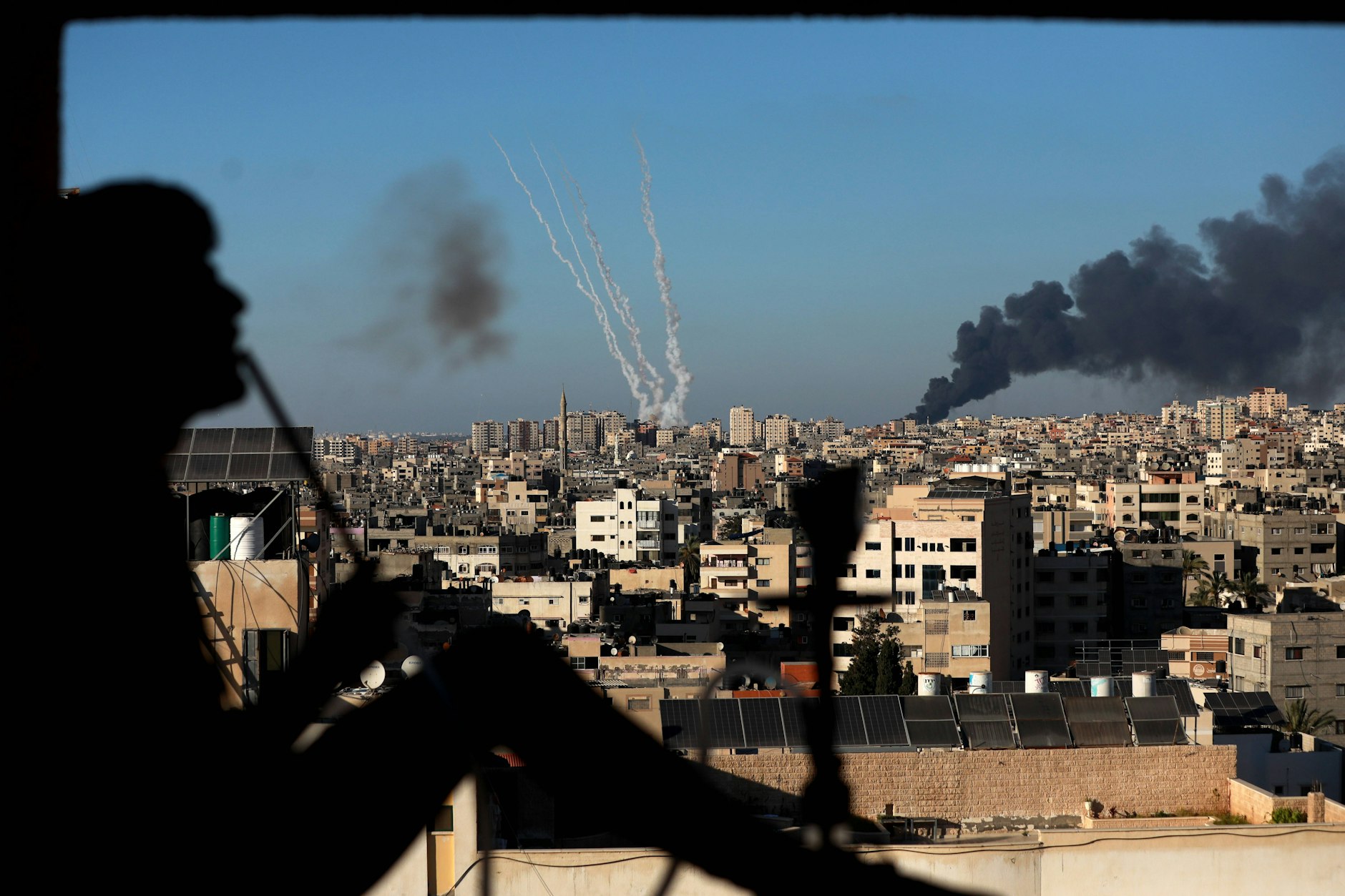 ARCHIV - Ein palästinensischer Mann raucht eine Wasserpfeife (Shisha oder Wasserpfeife), während im Gazastreifen Raketen und Rauch aufsteigen, im Mai 2021.