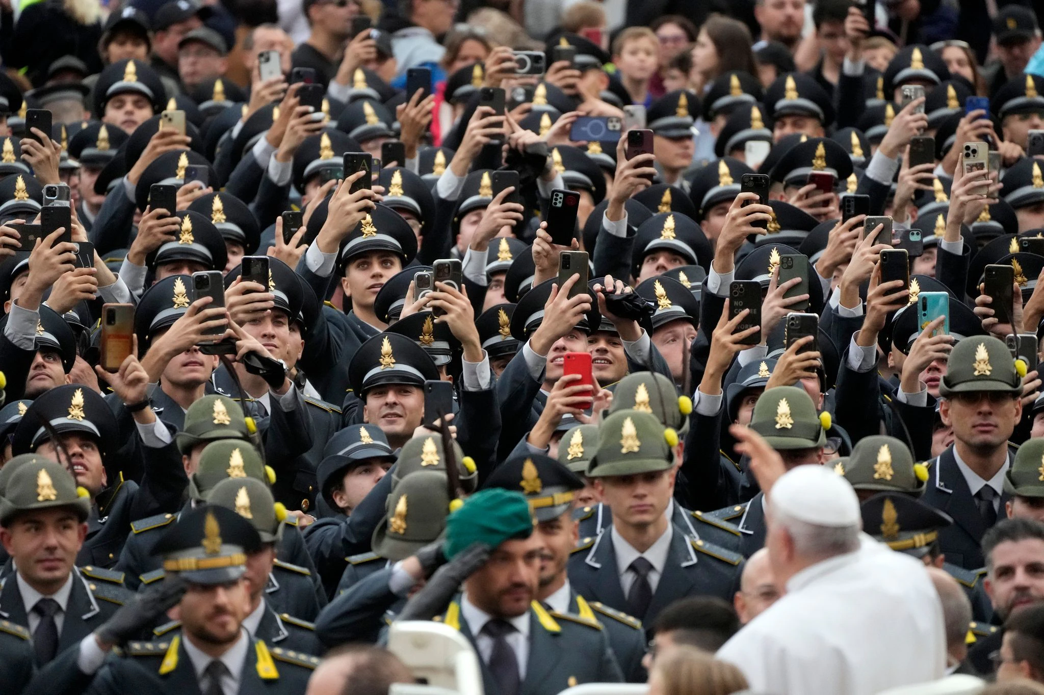 Polizisten filmen und salutieren Papst Franziskus bei seiner Ankunft zur wöchentlichen Generalaudienz auf dem Petersplatz im Vatikan.  