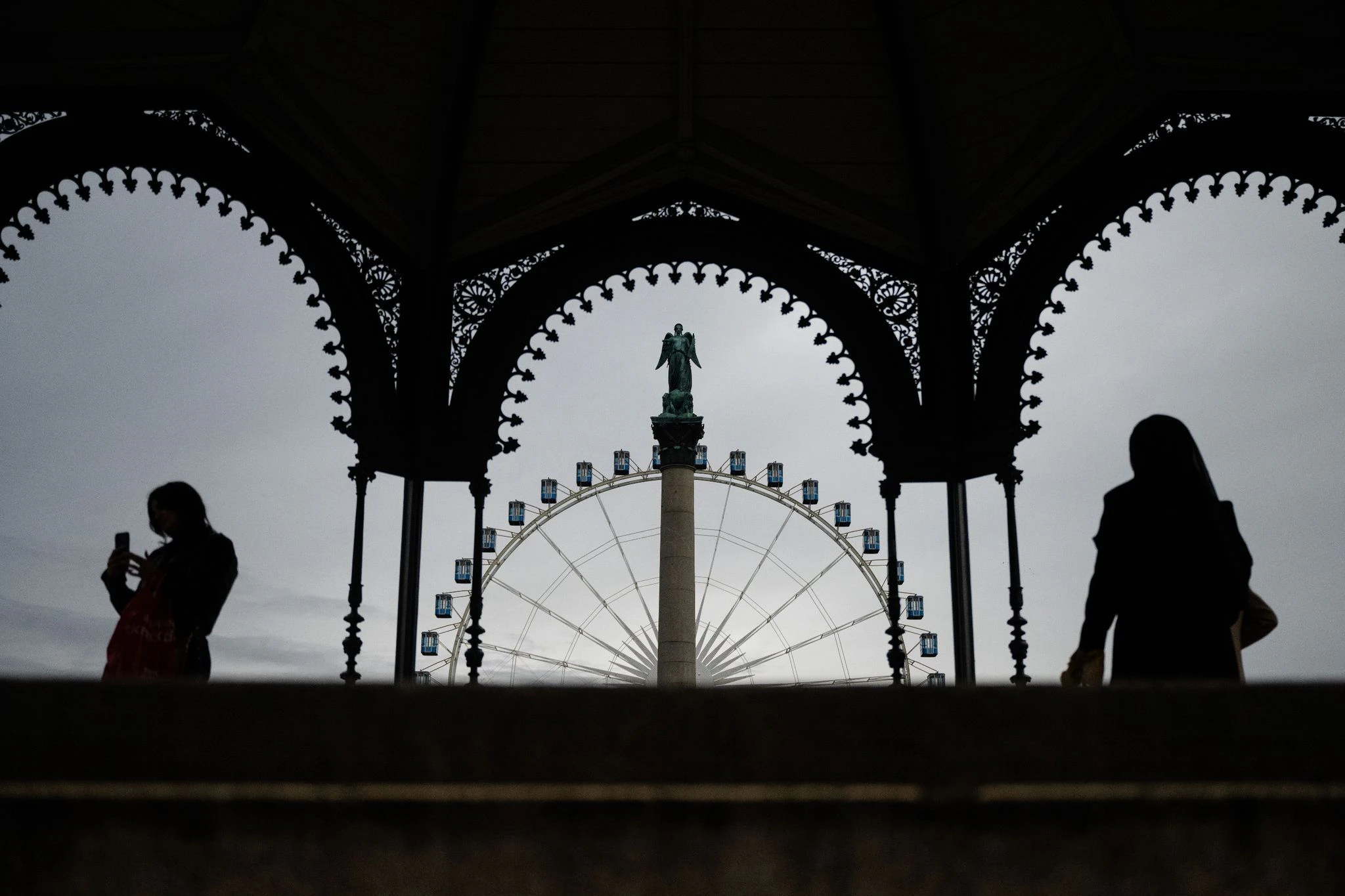 dpatopbilder - Zwei Frauen stehen im Musikpavillon auf dem Schlossplatz in Stuttgart, während im Hintergrund die Jubiläumssäule mit der Concordia-Statue und das Riesenrad zu sehen sind.  