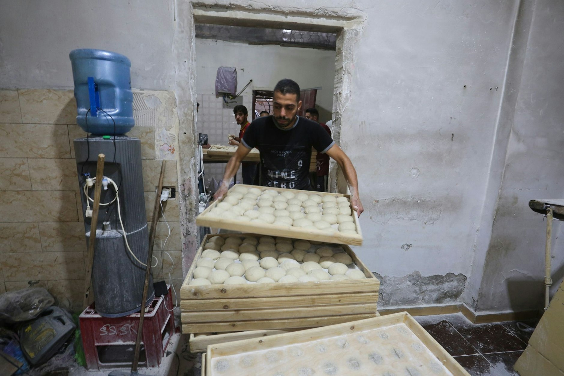 Palästinenser arbeiten in einer Bäckerei in Rafah. Vor dem Laden stehen bereits Menschen in einer Schlange, um Brot zu kaufen.