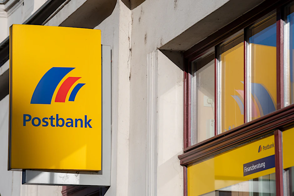 Ein Schild mit dem Logo der Postbank an der Fassade einer Filiale