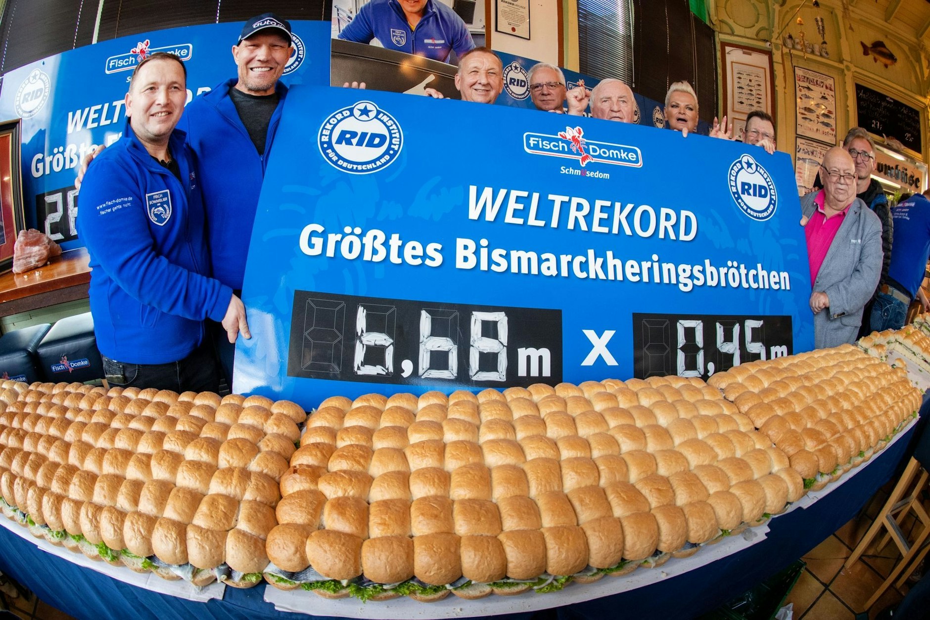 Axel Schulz, ehemaliger Profiboxer (2.v.r), André Domke (1.v.r), Fischsommelier und Fischhändler stehen am Weltrekord - größtes Bismarkheringsbrötchen. Es war demnach 6,68 Meter lang.  