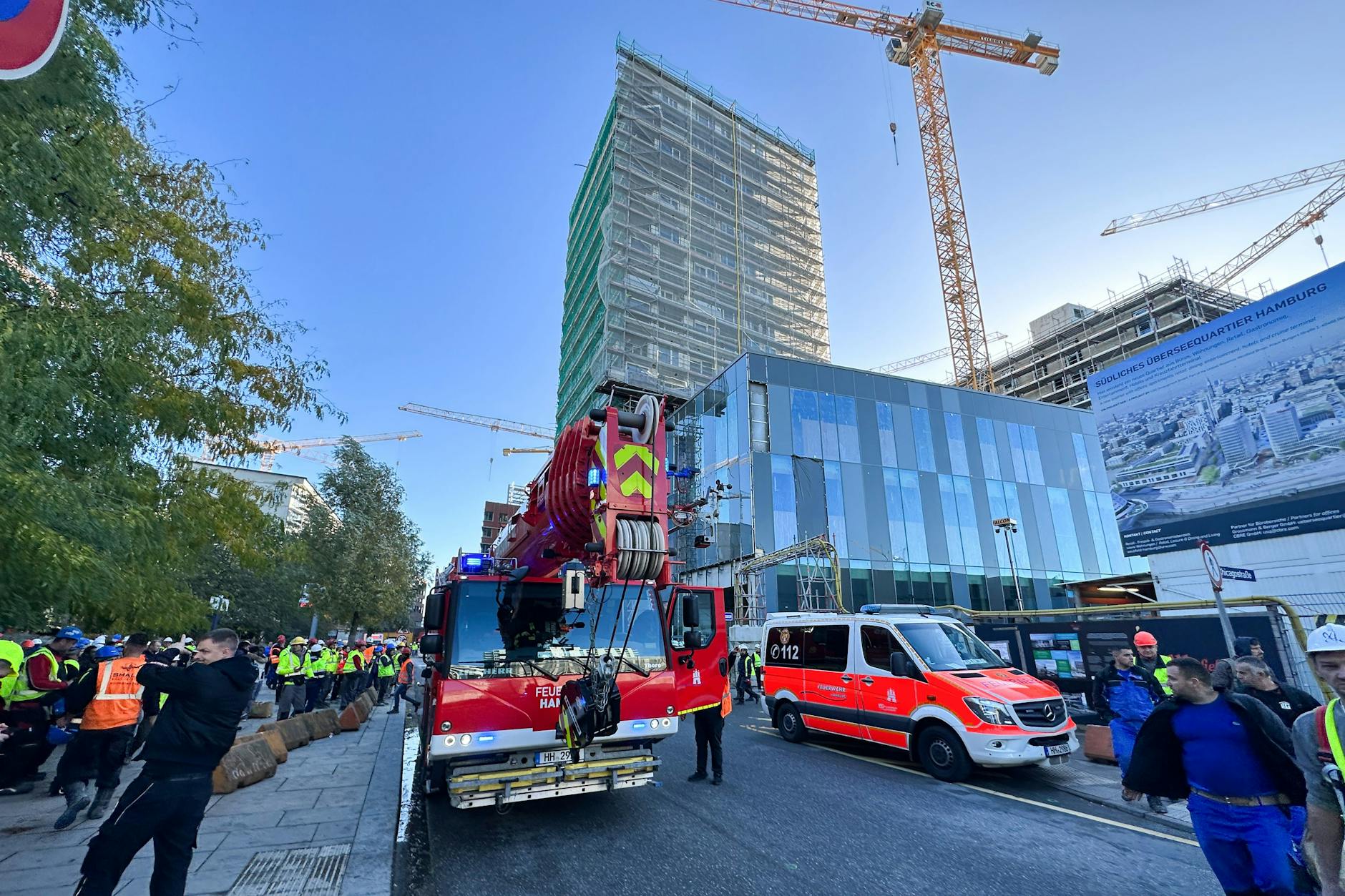 Einsatzfahrzeuge der Feuerwehr stehen vor einem eingerüsteten Hochhaus. Auf einer Baustelle in der Hamburger HafenCity sind am Montag mehrere Arbeiter von einem Gerüst gestürzt.
