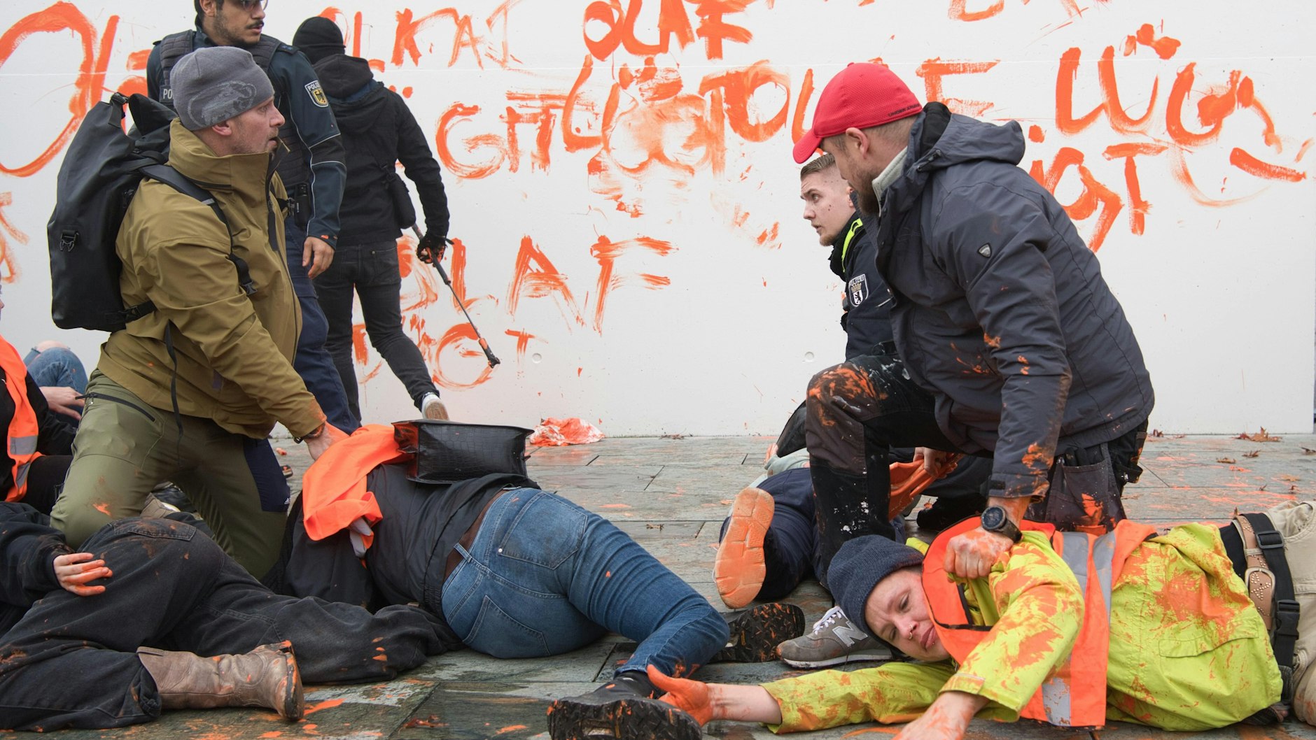 Aktivisten der Gruppe Letzte Generation werden vor dem Kanzleramt von Polizeibeamten festgehalten. Zuvor hatten sie eine Wand des Kanzleramtes bemalt.