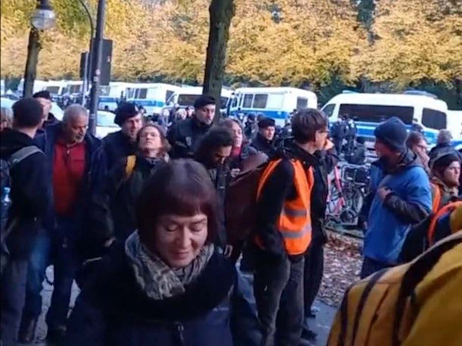 Ein Video auf X zeigt, wie ein Polizist eine Aktivistin (links im Bild mit gelbem Rucksack) kraftvoll zu Boden stößt.