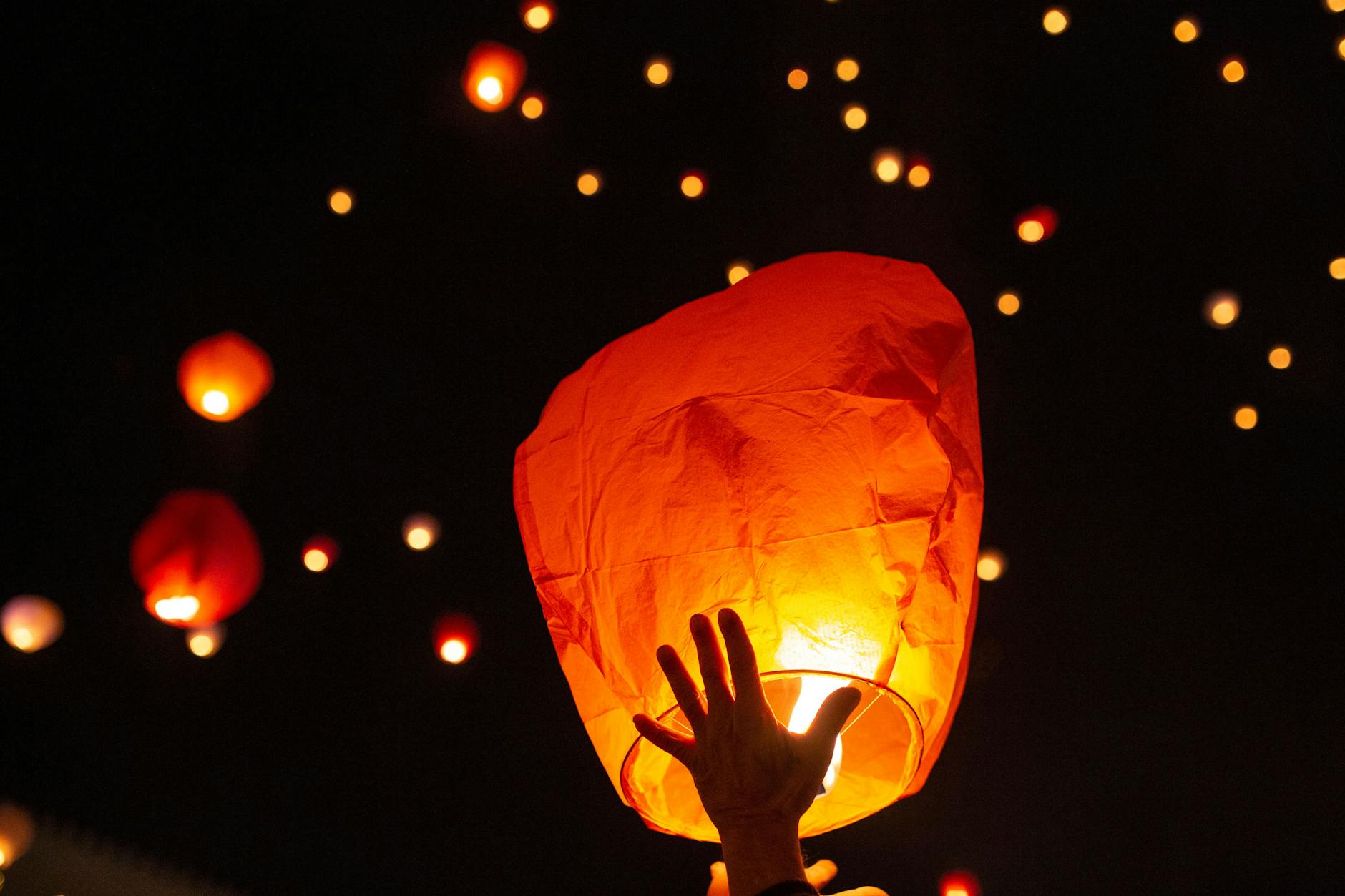 Menschen entlassen ihre brennenden Himmelslaternen in den nächtlichen Himmel. 