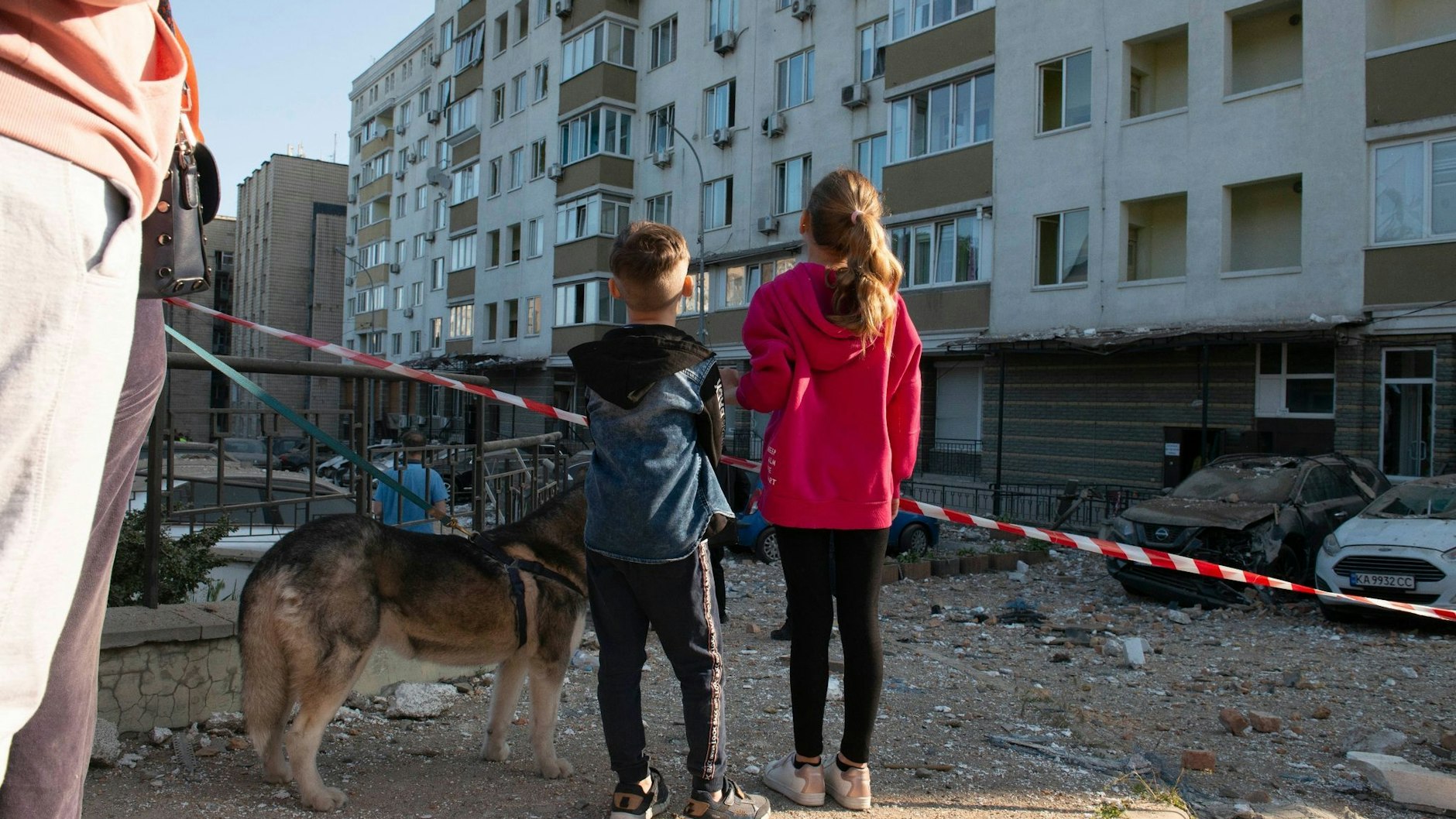 Kinder schauen in Kiew auf ein bei russischen Raketenangriffen beschädigtes Gebäude. 