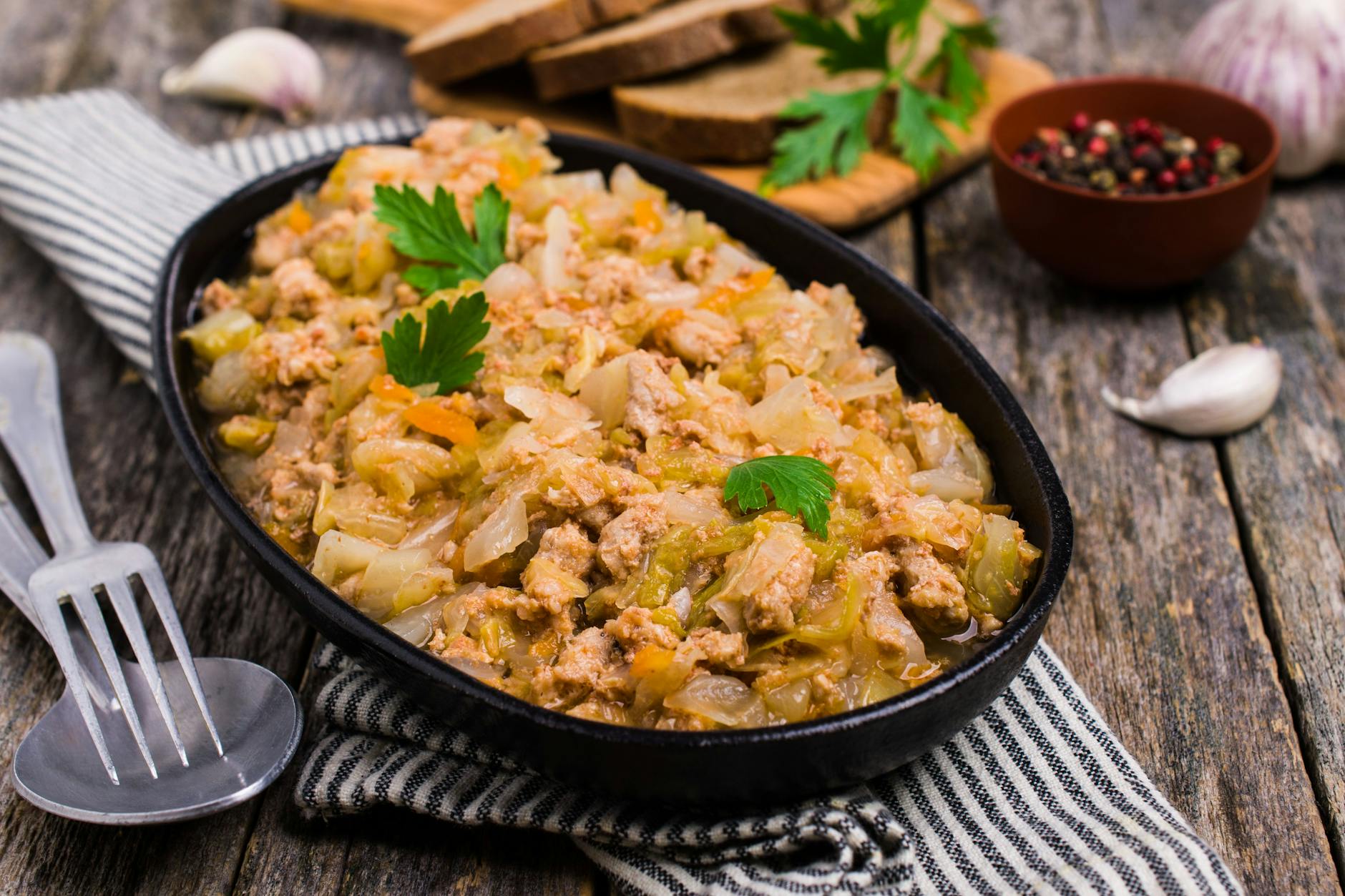 Eine dampfende Portion cremige Spitzkohlpfanne mit Hackfleisch, Kartoffeln und Karotten, serviert auf einem Teller.