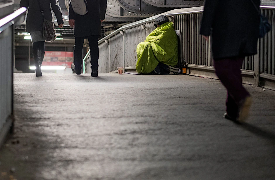 Ein Obdachloser mit Sammelbecher auf der Bahnbrücke am Bahnhof Friedrichstraße.