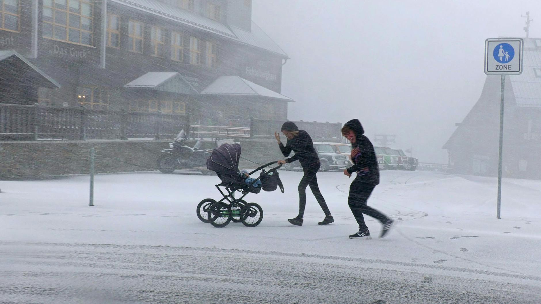 Erster Schnee in Oberwiesenthal: Menschen waren Mitte Oktober im Schneetreiben auf dem Fichtelberg unterwegs.