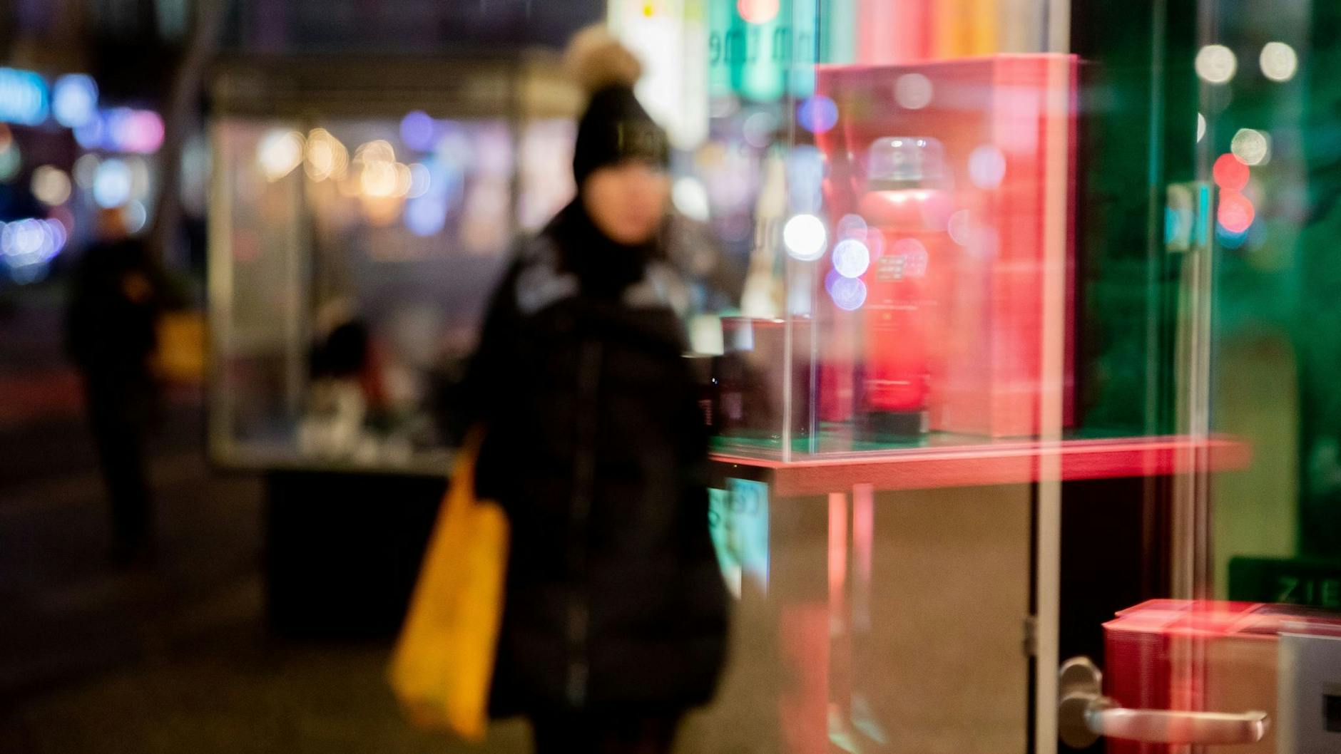 Die Umrisse einer Passantin spiegeln sich in einem Schaufenster. Viele Menschen können in diesem Jahr weniger Geld für Weihnachtsgeschenke ausgeben.