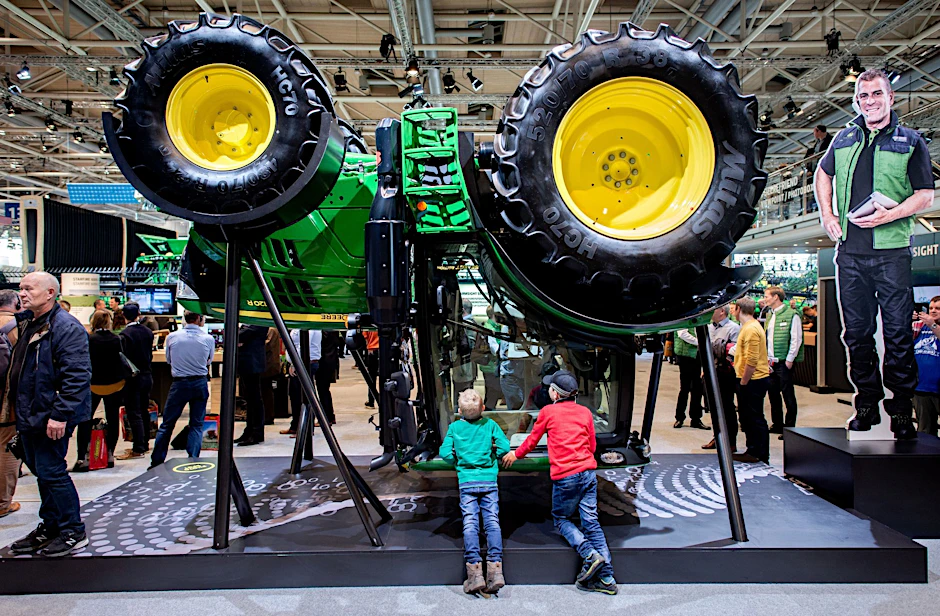 ARCHIV - Zwei Jungen betrachten am Stand von John Deere auf der Landtechnik-Messe Agritechnica in der Messe Hannover einen Traktor, der für die Präsentation umgedreht wurde.  