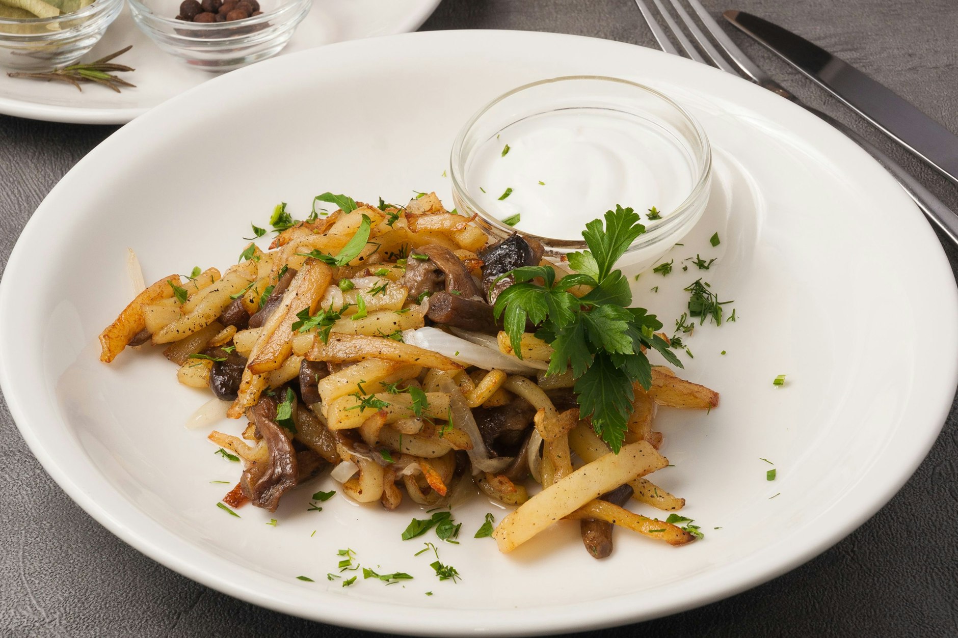 Eine Portion Bratkartoffeln de luxe mit Pilzen, Speck und frischen Kräutern.
