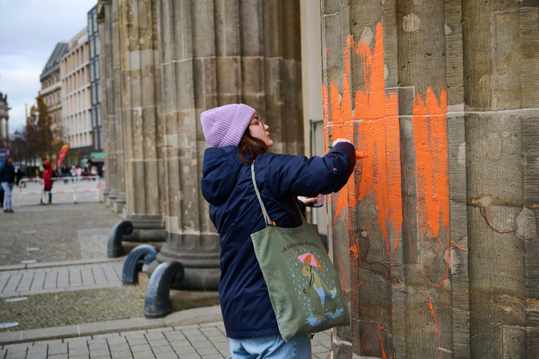 Eine Aktivistin der Letzten Generation bemalt das Brandenburger Tor.