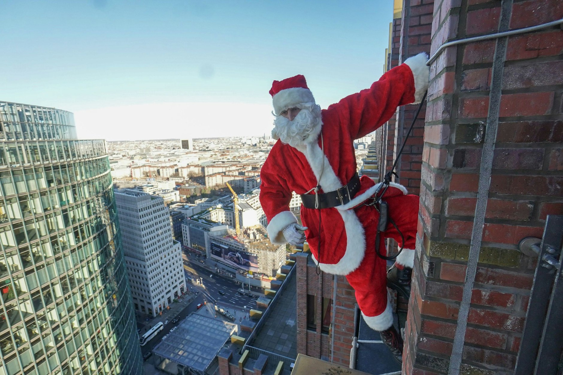 Kommt er oder kommt er nicht: Hier hängt der Weihnachtsmann bei einer Kletteraktion in luftiger Höhe an der Fassade des Panoramapunkts auf dem Potsdamer Platz.