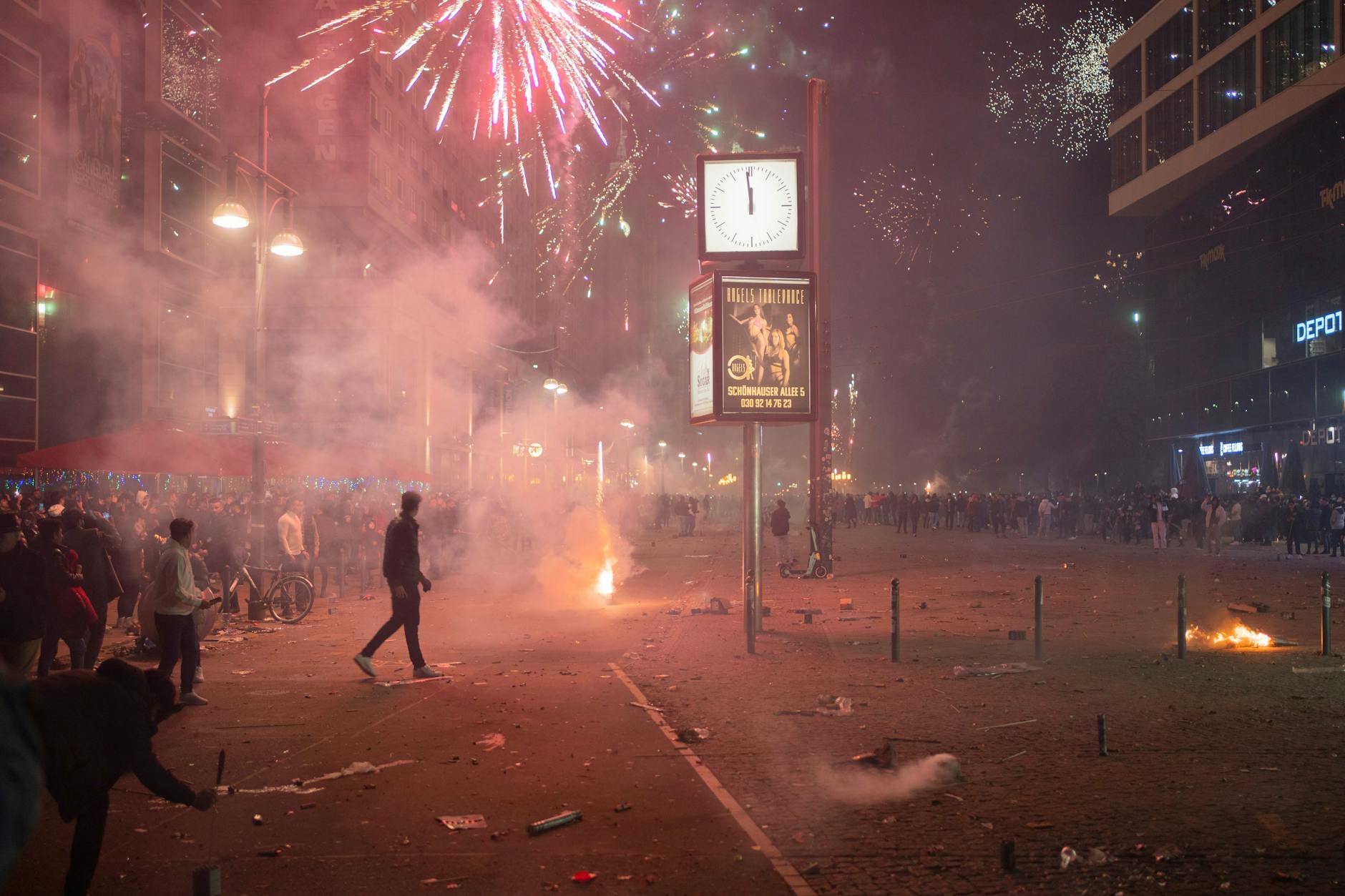 Menschen feiern Silvester mit Feuerwerk auf dem Alexanderplatz.