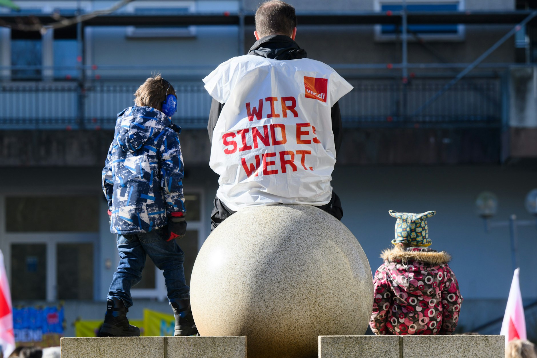 Ein Erzieher einer Kindertagesstätte sitzt mit einer Verdi-Weste bei einem Warnstreik.