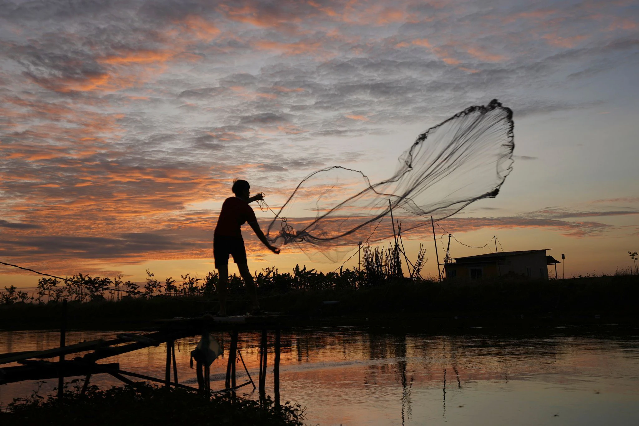 Ein Fischer wirft sein Netz in einem Kanal im Dorf Tuol außerhalb von Kambodschas Hauptstadt Phnom Penh aus.  