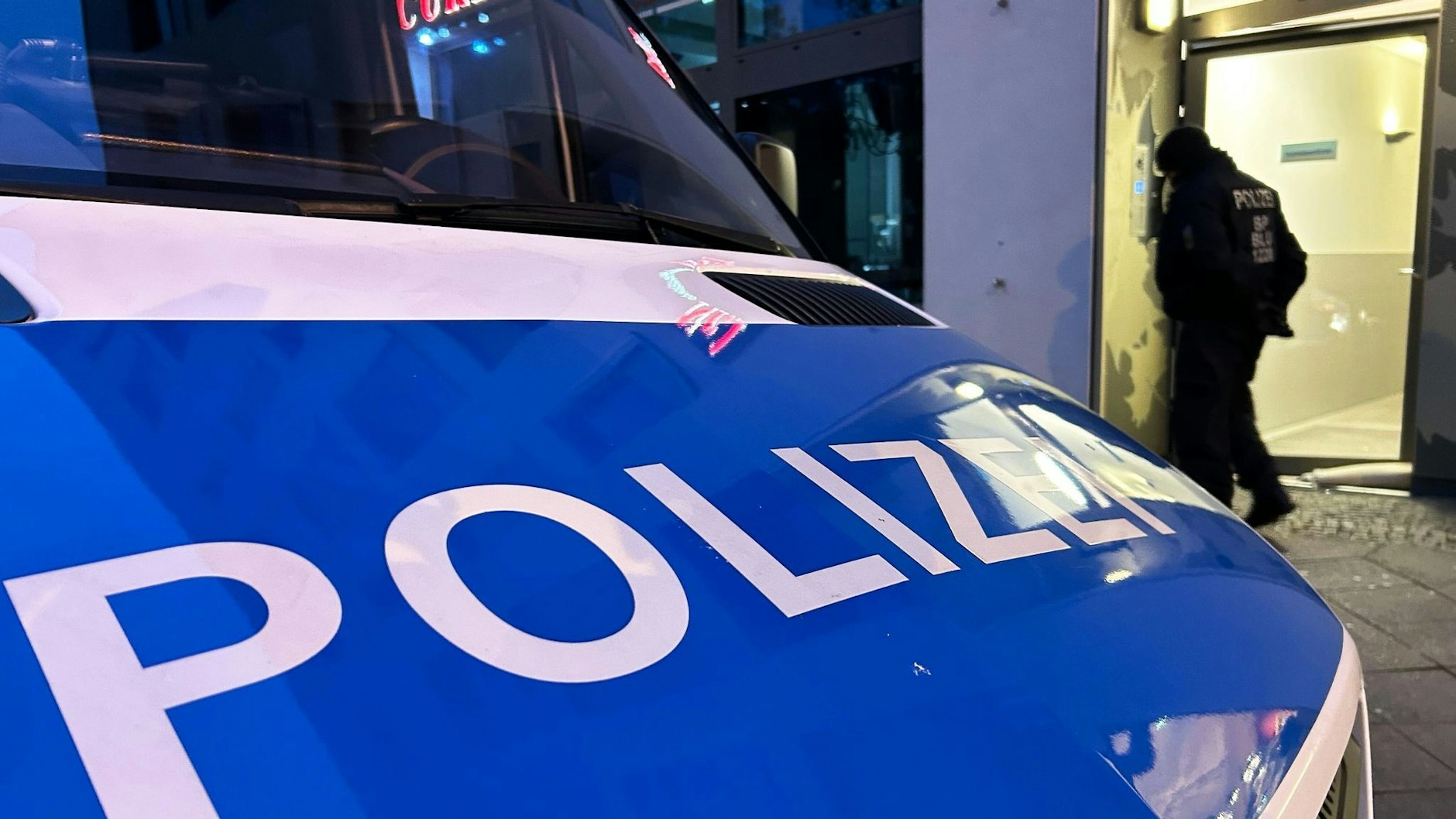 Ein Einsatzfahrzeug der Polizei steht bei einer Razzia in Berlin-Adlershof auf der Straße. 