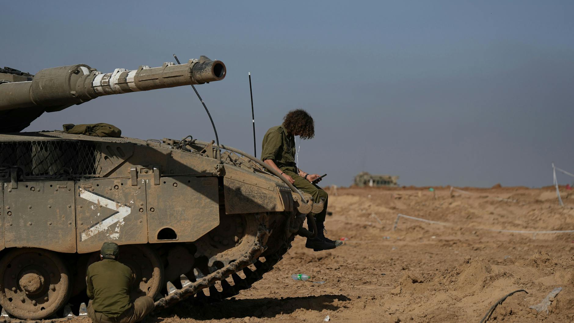 Feuerpause: Ein israelischer Soldat sitzt auf einem Panzer und schaut auf sein Smartphone.
