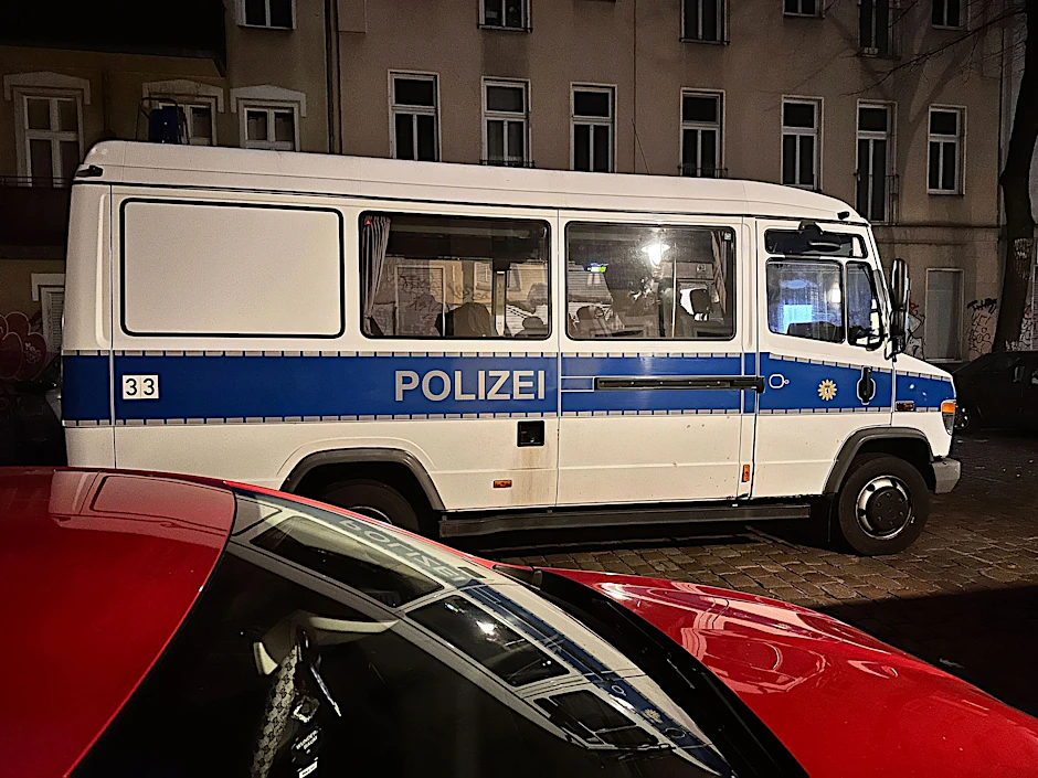 Ein Einsatzfahrzeug der Polizei steht bei einer Razzia in Berlin-Friedrichshain auf der Straße.  