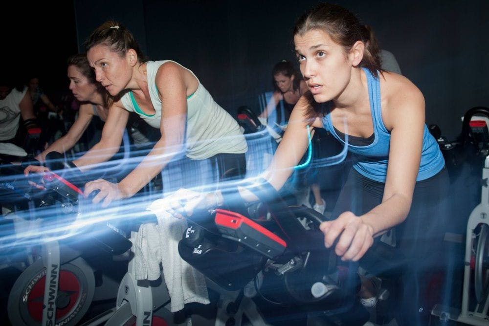 Indoor-Cycling einfach erklärt: zu Techno-Beats in die Pedale treten und dabei schwitzen, bis der Arzt kommt.