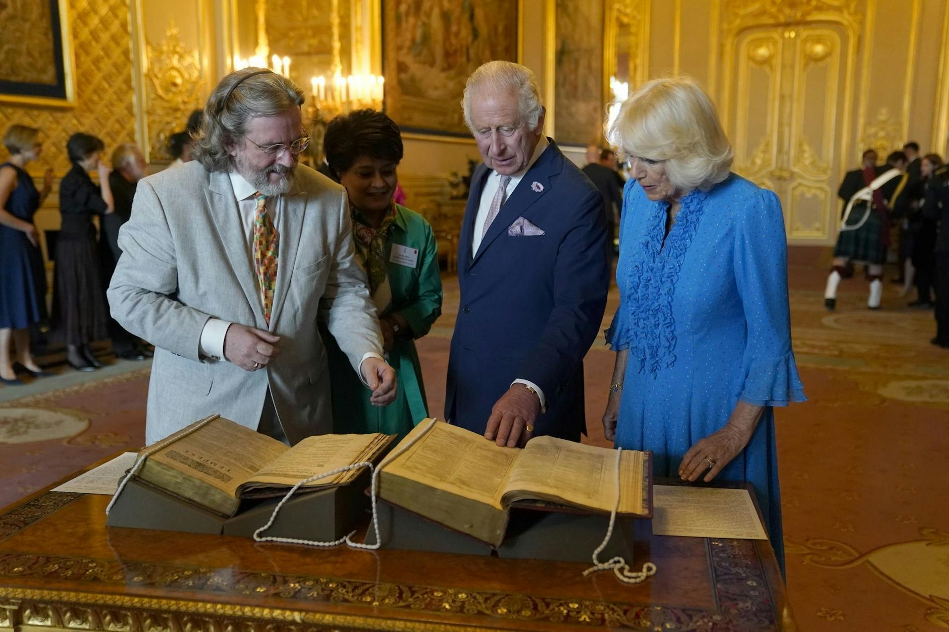 ARCHIV - König Charles III. und Königin Camilla betrachten das erste Shakespeare-Folio während eines Empfangs auf Schloss Windsor.