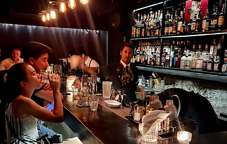 Gäste sitzen am Tresen einer Bar in Bangkok.  