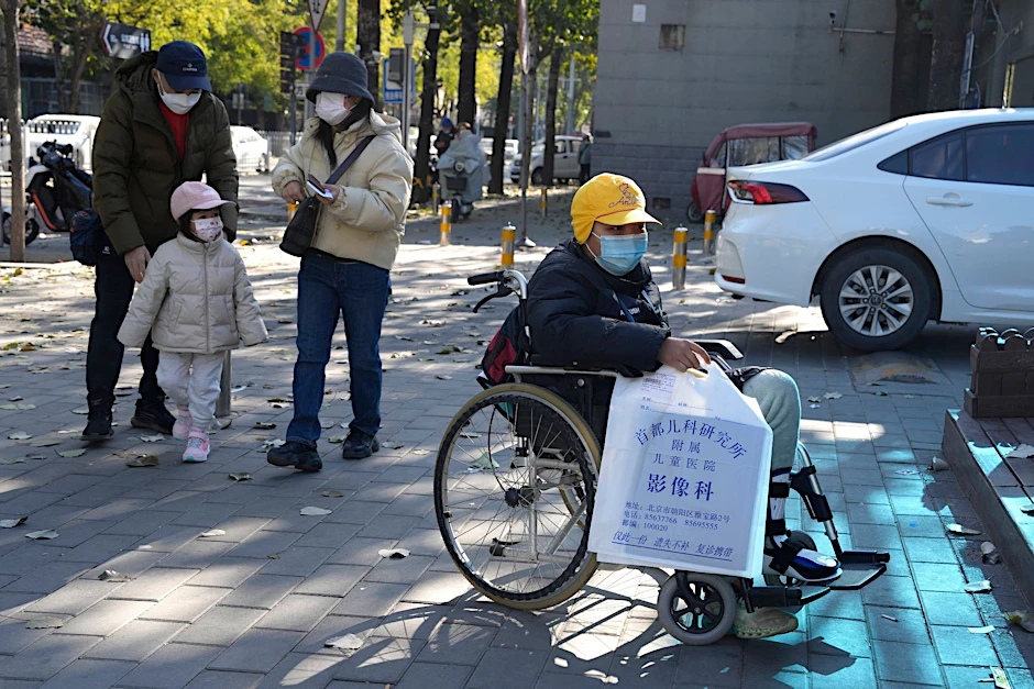 Ein Junge in einem Rollstuhl hält in Peking eine Tasche aus der radiologischen Abteilung eines Kinderkrankenhauses. In den vergangenen Tagen hatten Berichte über die starke Häufung von Atemwegserkrankungen bei Kindern Sorgen aufkommen lassen.  