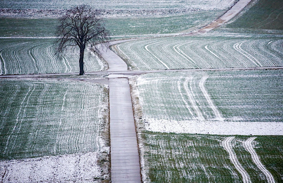 Schnee liegt am Morgen auf Feldern.  