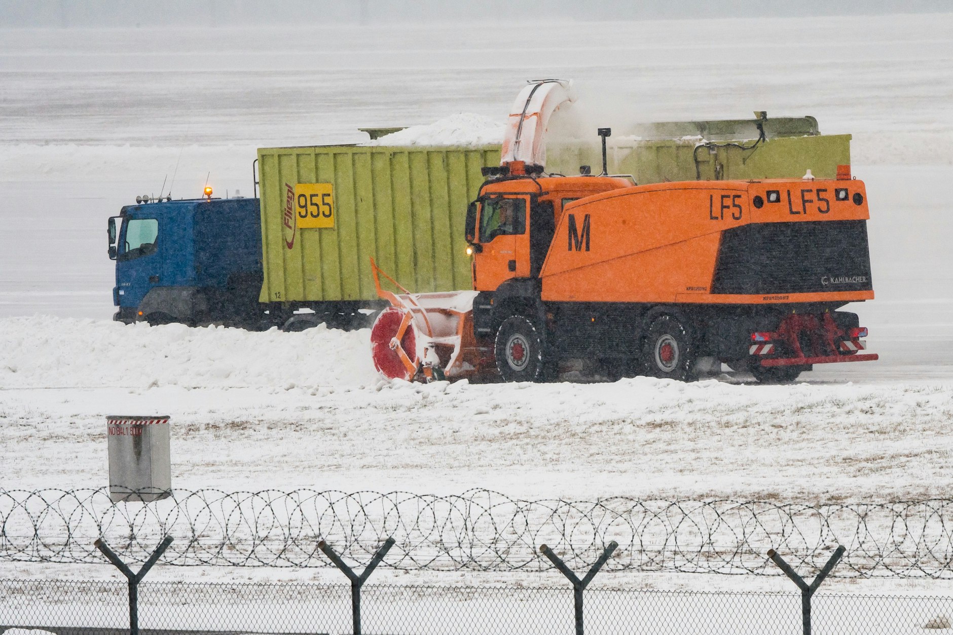 Eine Schneefräse, ein Containerfahrzeug und ein Traktor mit Schneepflug befreien eine Startbahn auf dem Flughafen München vom Schnee (Archivbild).