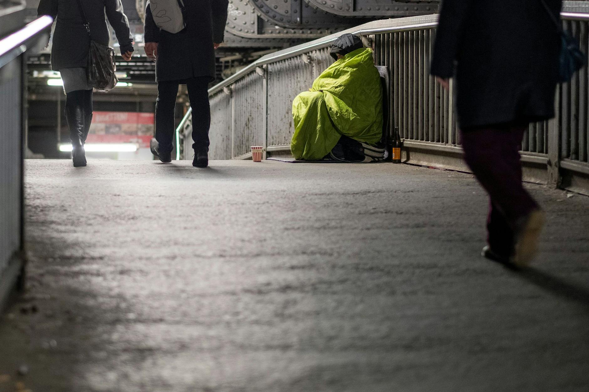 Ein Obdachloser mit Sammelbecher auf der Bahnbrücke am Bahnhof Friedrichstraße. 