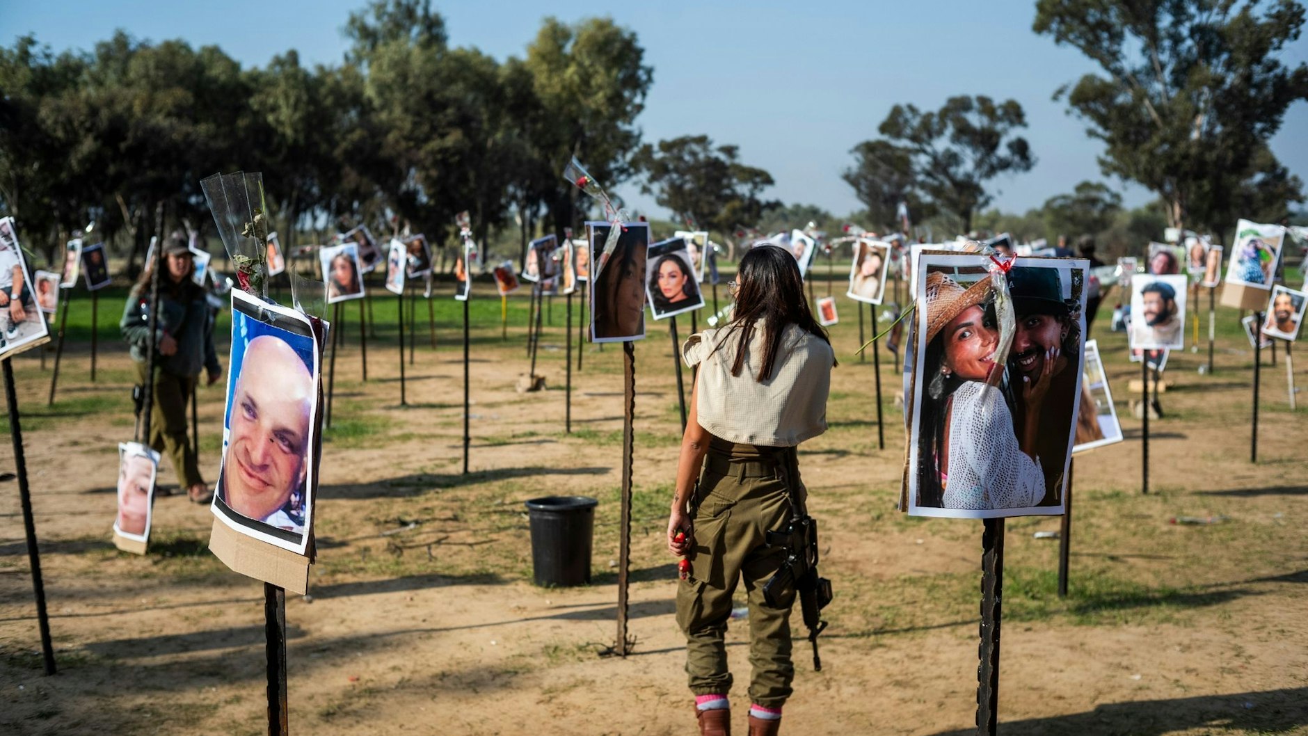 Israelische Soldatinnen stehen zwischen Fotos getöteter Israelis am Ort des Hamas-Massakers beim Musikfestival in der Negev-Wüste am 7. Oktober. Foto:&nbsp;