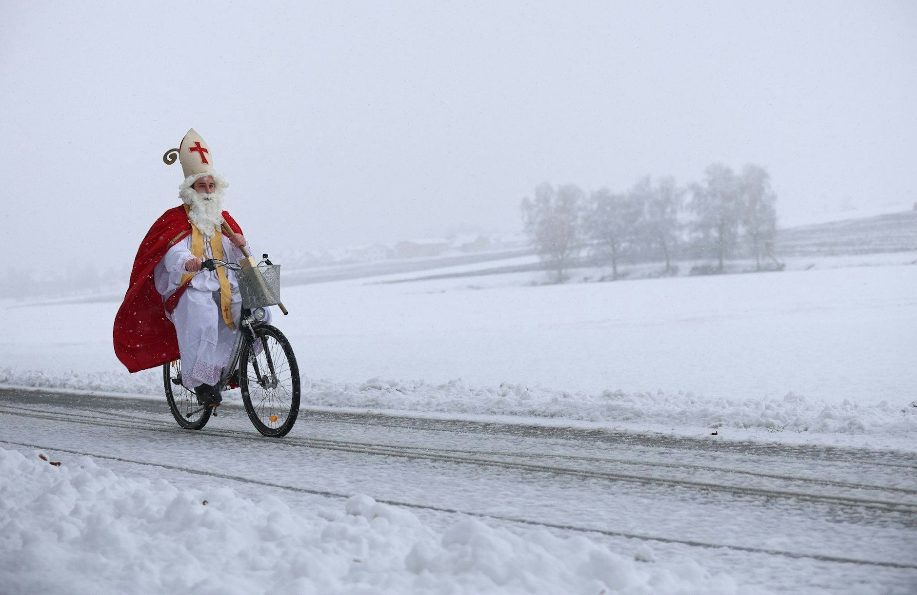 Pünktlich zum Beginn des Dezembers ist der Nikolaus unterwegs: Schnee kann ihn nicht aufhalten. Hier ist er nahe Betzenweiler (Baden-Württemberg) mit dem Fahrrad unterwegs zu einer Weihnachtsfeier.  
