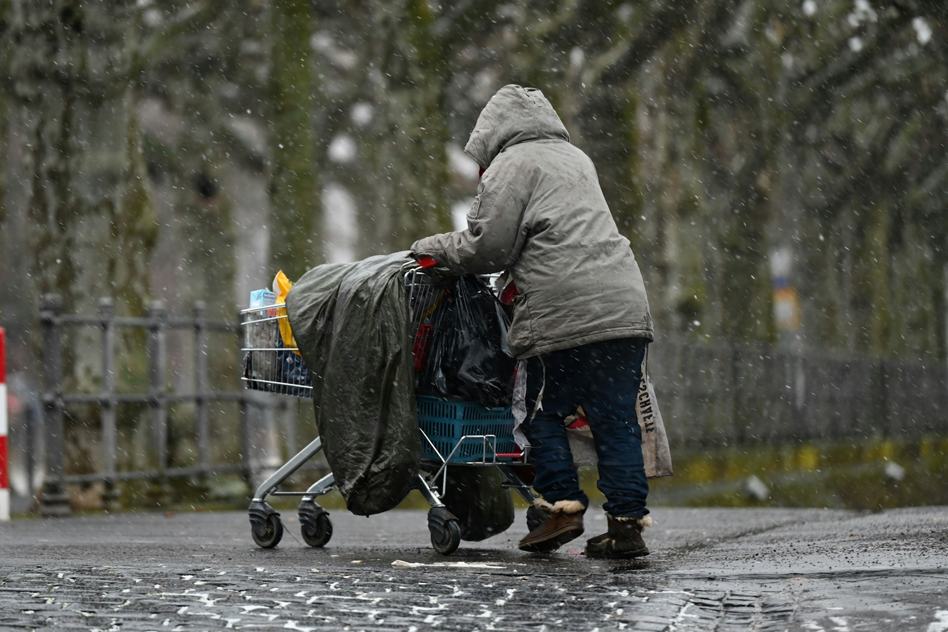 Obdachlose: Eine obdachlose Frau schiebt ihre Sachen in einem Einkaufswagen.